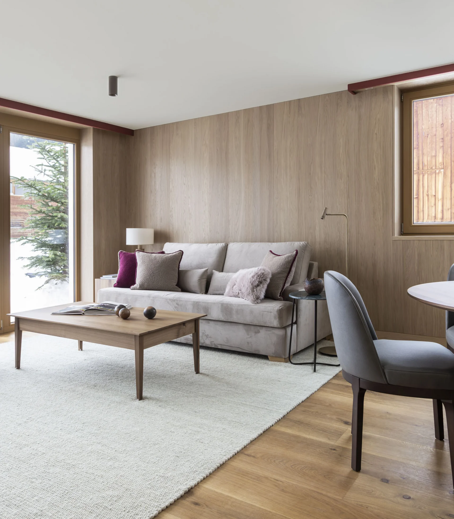 Gemütliches Wohnzimmer mit Sofa, Sesseln, Esstisch und großen Fenstern mit Bergblick