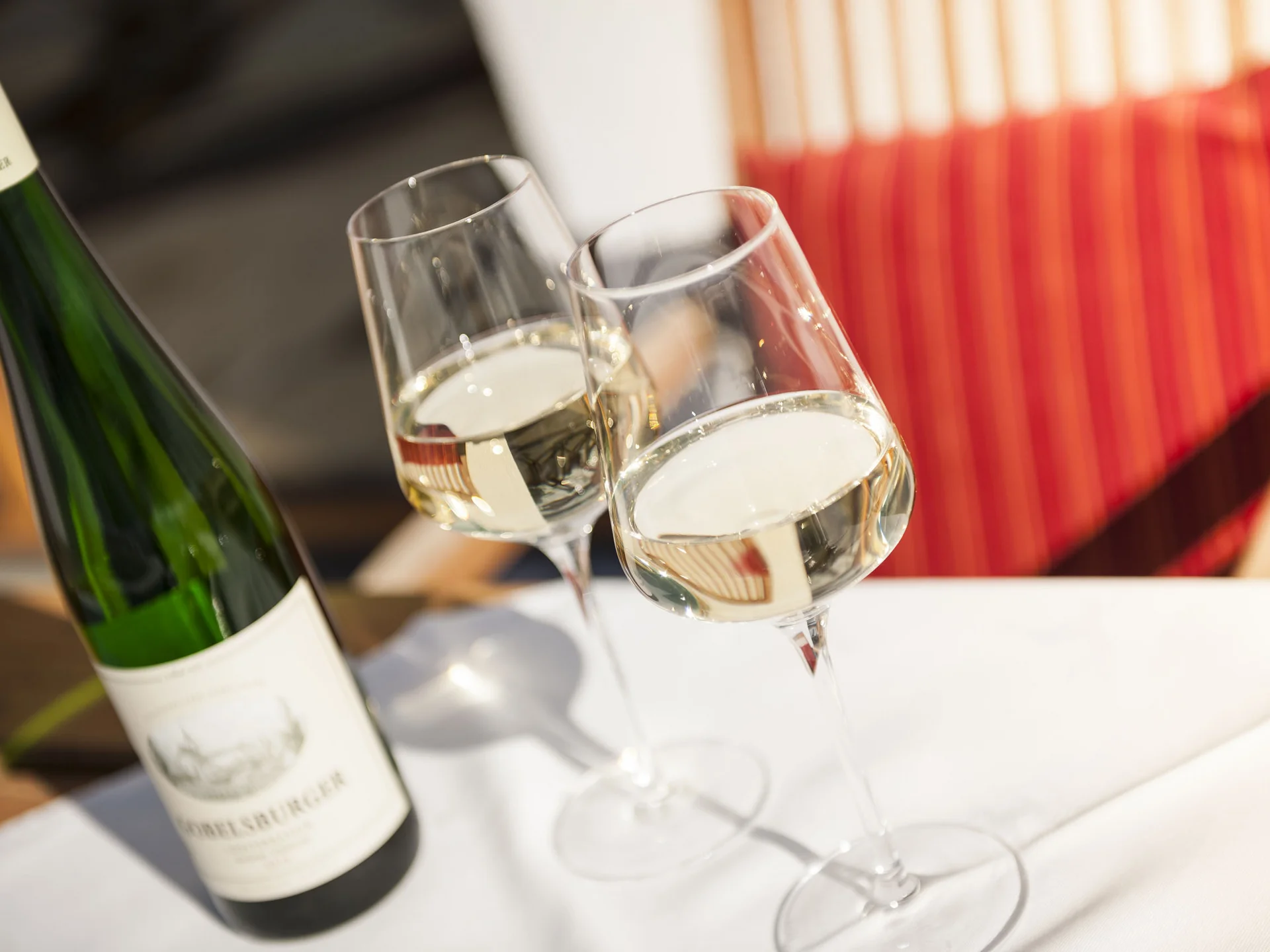 Zwei Sektgläser stoßen mit einer geöffneten Sektflasche an