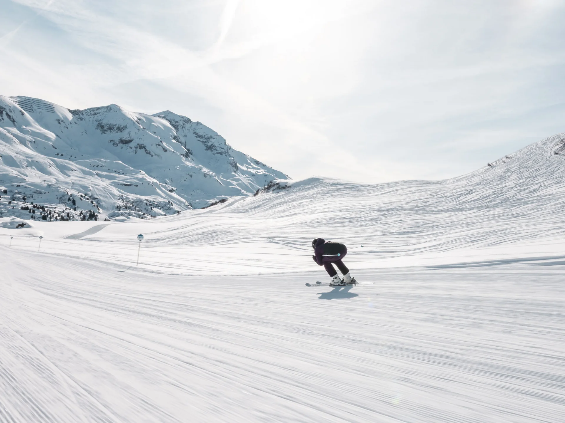 Skifahrer auf breiter, schneebedeckter Piste mit Bergen im Hintergrund
