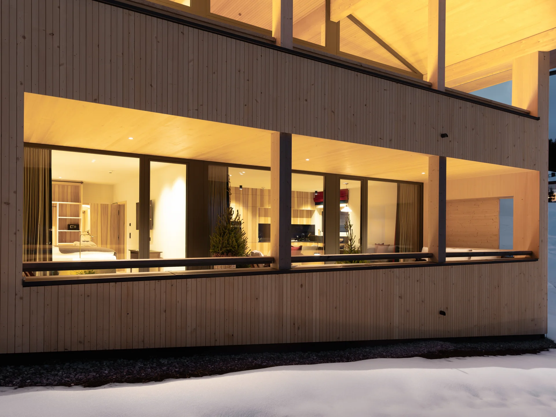 Beleuchtetes modernes Holzhaus bei Schnee am Abend