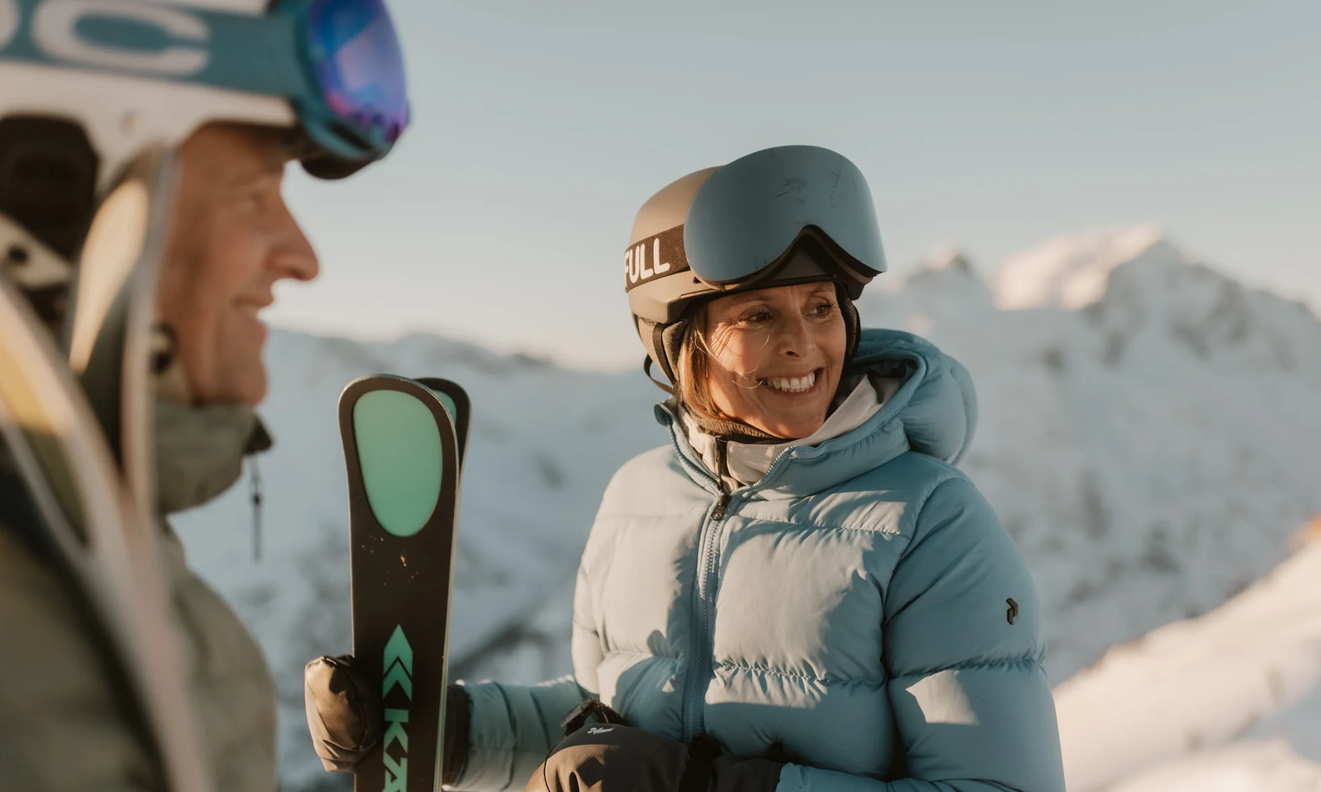 Zwei Skifahrer mit Helmen und Skiern im Schnee vor Berglandschaft