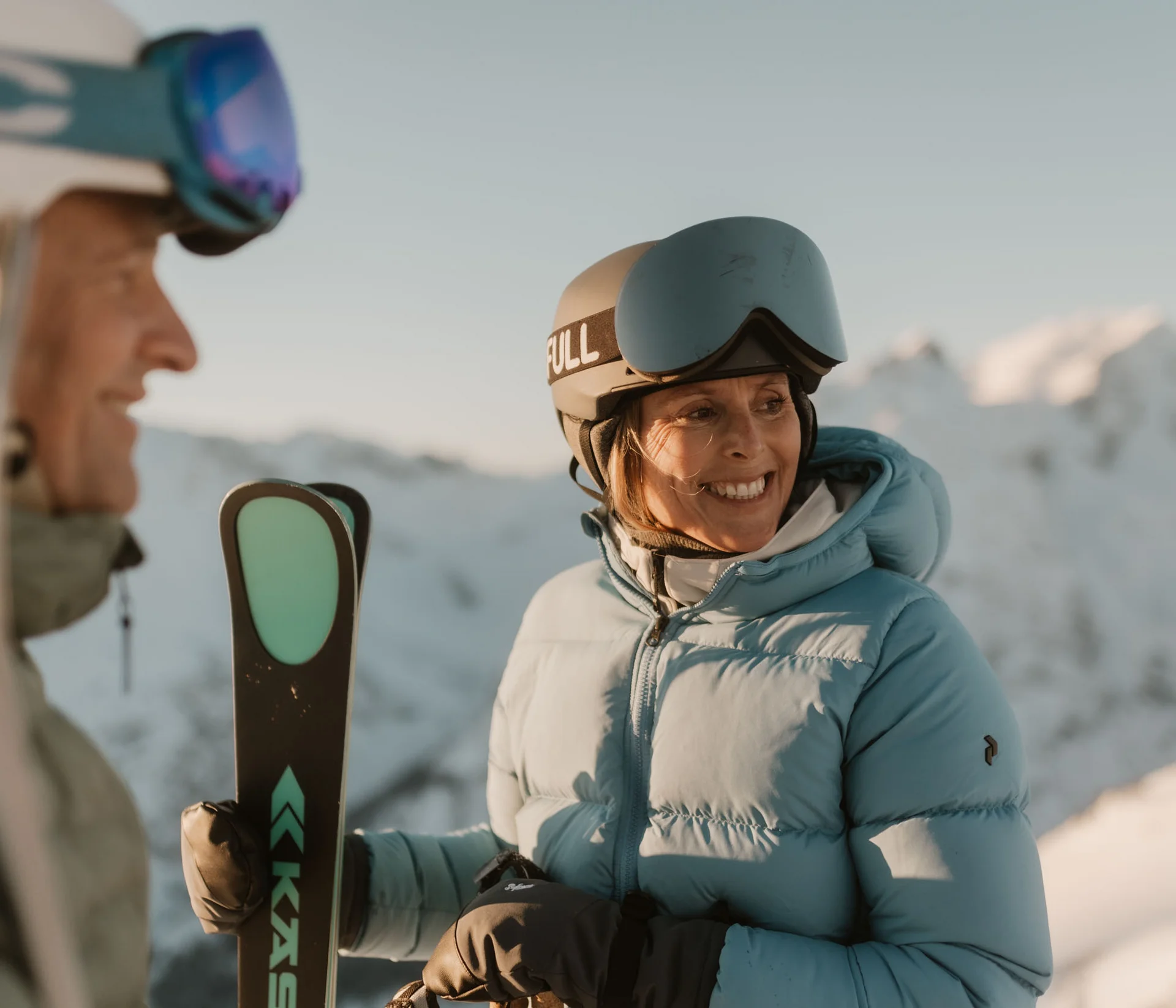 Zwei Skifahrer mit Helmen und Skiern im Schnee vor Berglandschaft