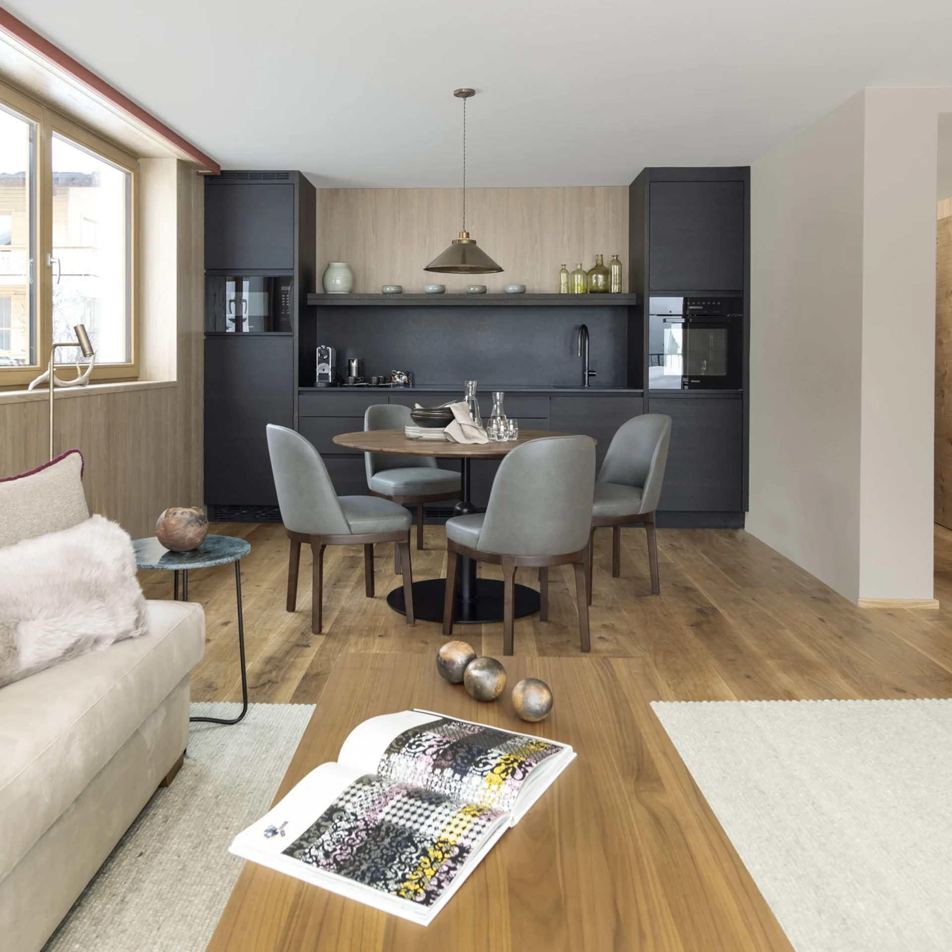 Moderner Wohn- und Essbereich mit schwarzer Küche und Holzboden