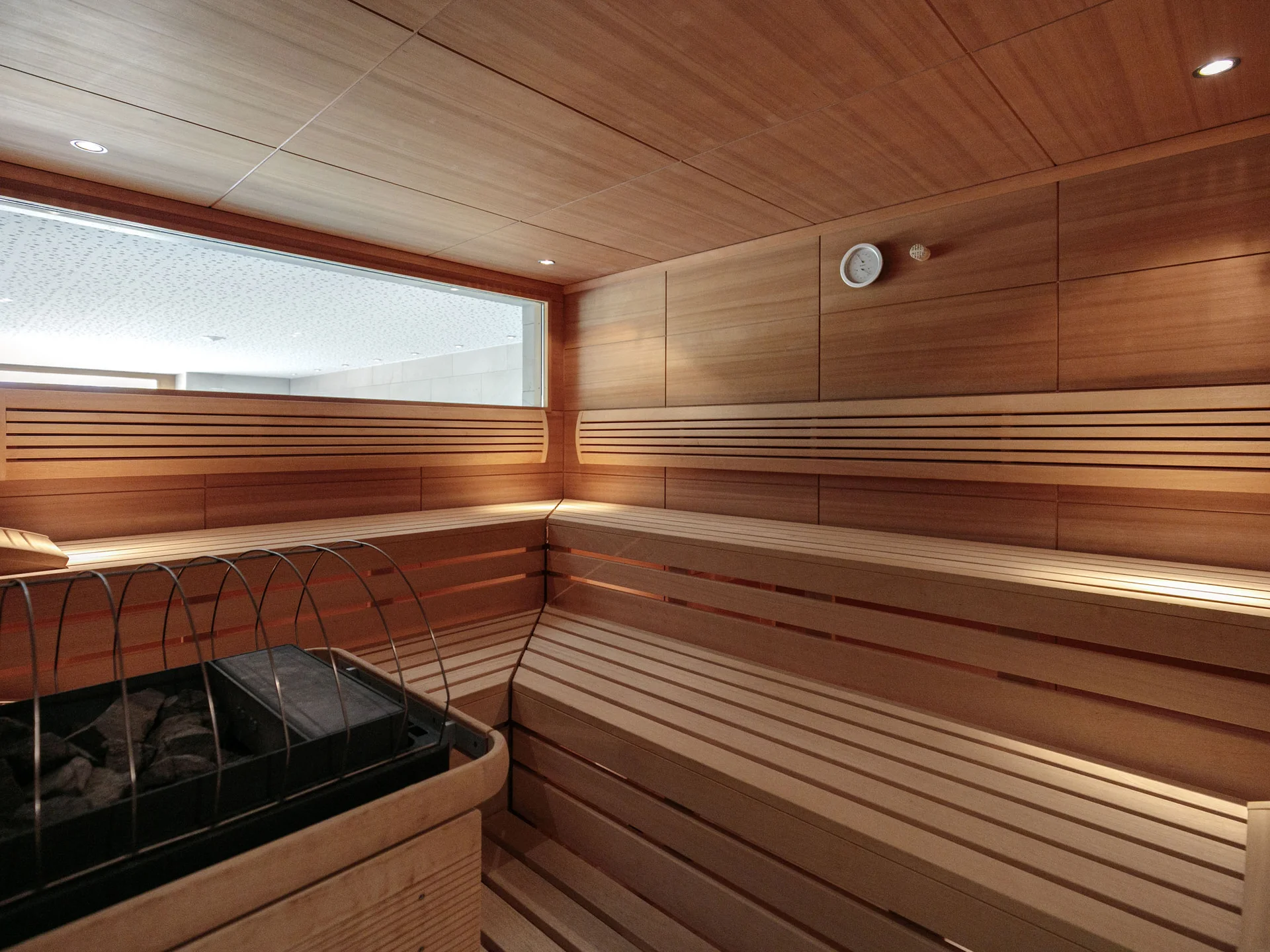 Innenansicht einer Holzsauna mit Ofen und Sitzbänken