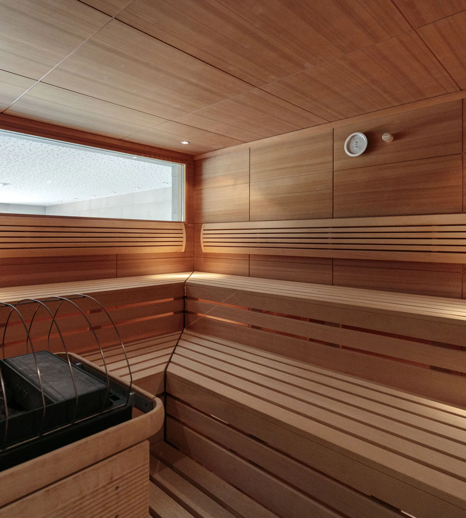 Innenansicht einer Holzsauna mit Ofen und Sitzbänken