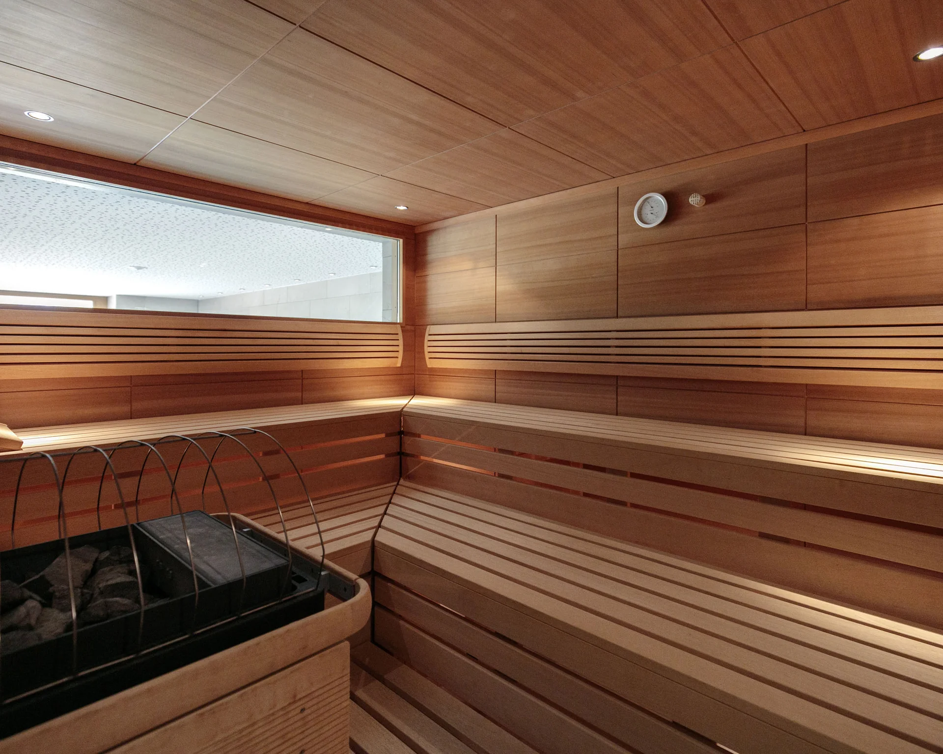 Innenansicht einer Holzsauna mit Ofen und Sitzbänken