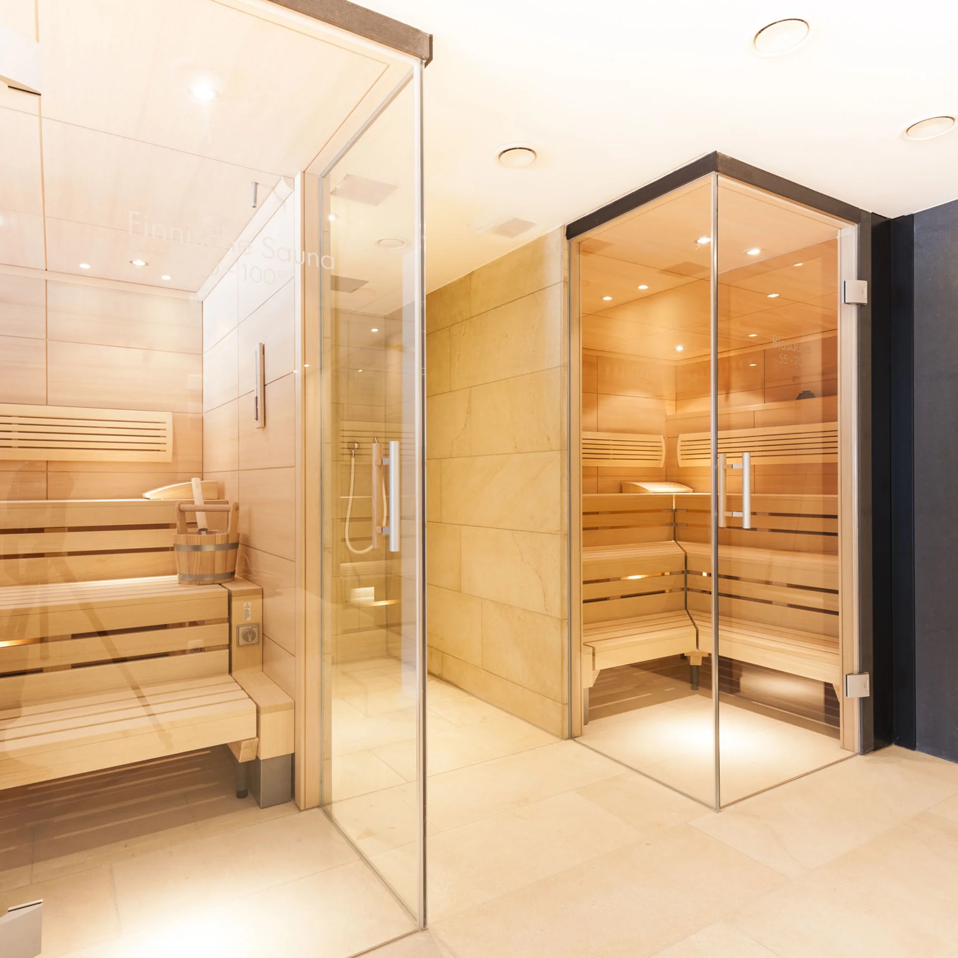Moderne Saunakabinen mit Holzbänken und Glaswänden in einem hellen Raum