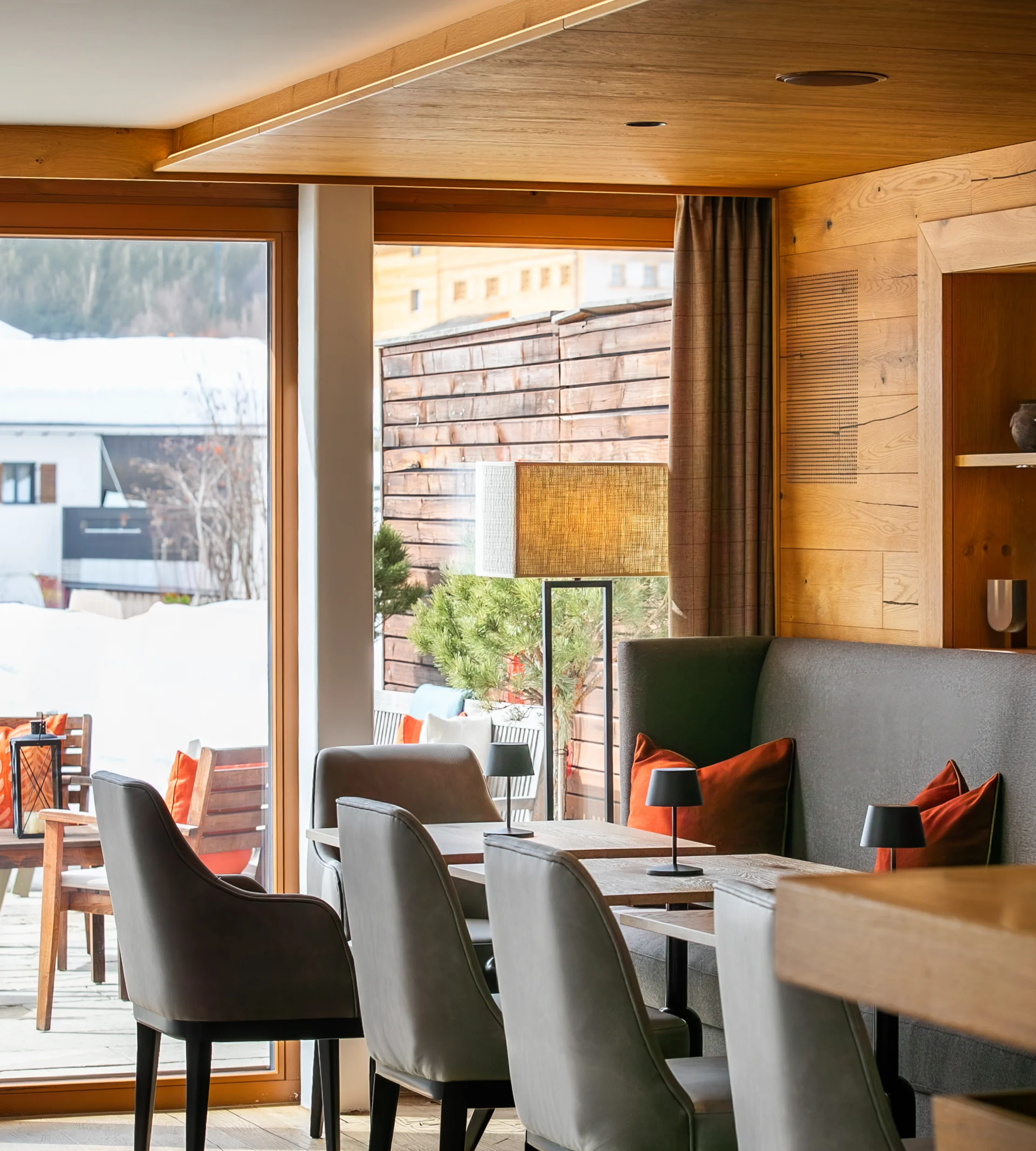 Moderner Gastraum mit Holzdecke und Sitzbereich neben großen Fenstern im Winter