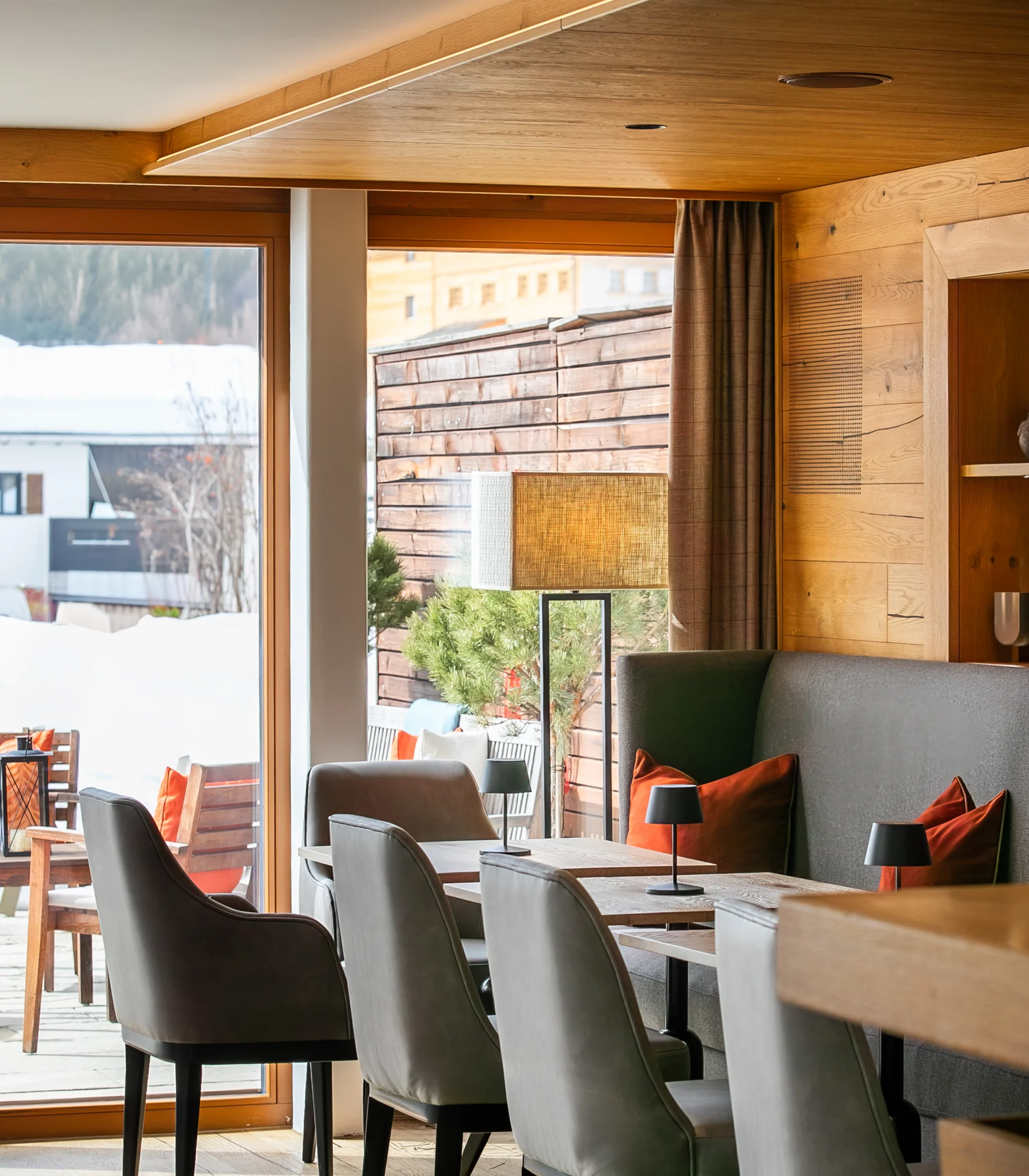 Ihr Hotel in Lech am Arlberg. Das Sunora. Moderner Gastraum mit Holzdecke und Sitzbereich neben großen Fenstern im Winter