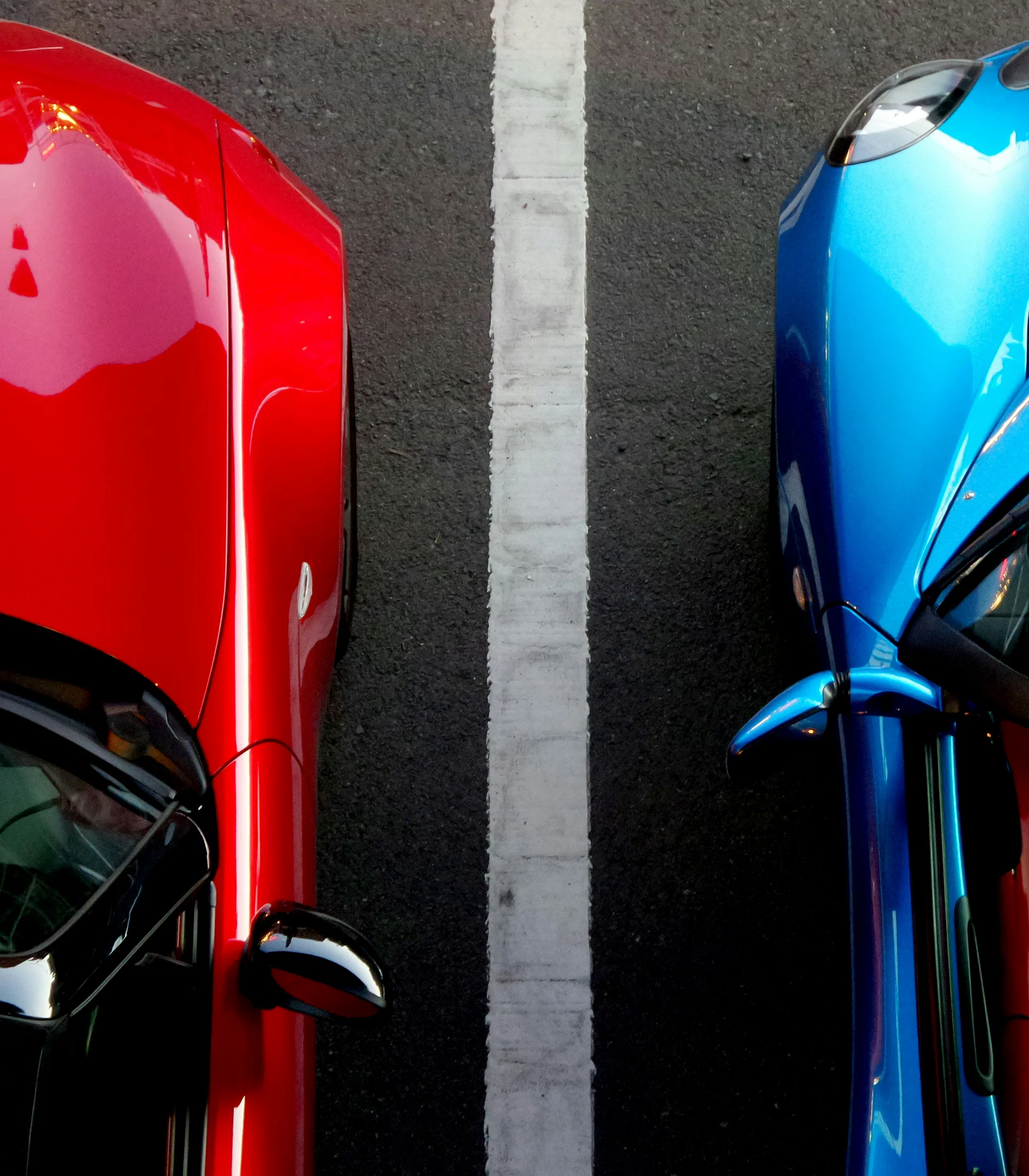 Nahaufnahme von zwei nebeneinander parkenden roten und blauen Autos