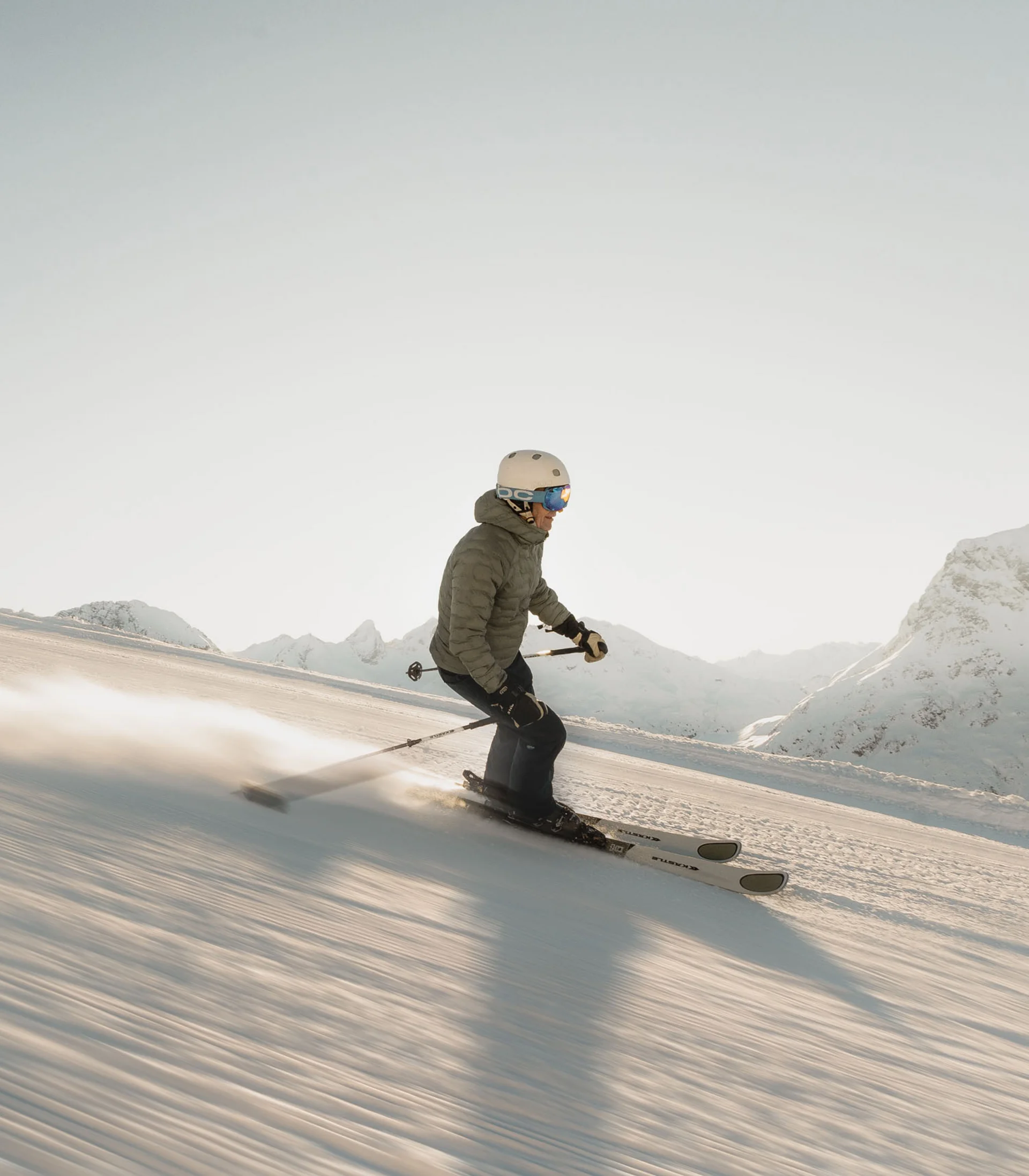 Skifahrer fährt bei klarem Himmel auf präparierter Piste in den Bergen