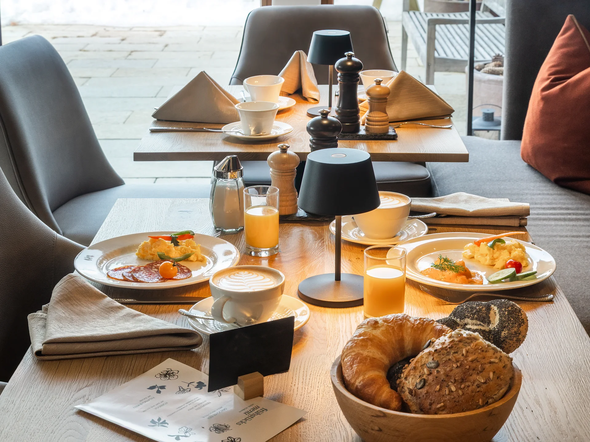Frühstückstisch mit Kaffee, Säften, Gebäck und Besteck in gemütlichem Raum