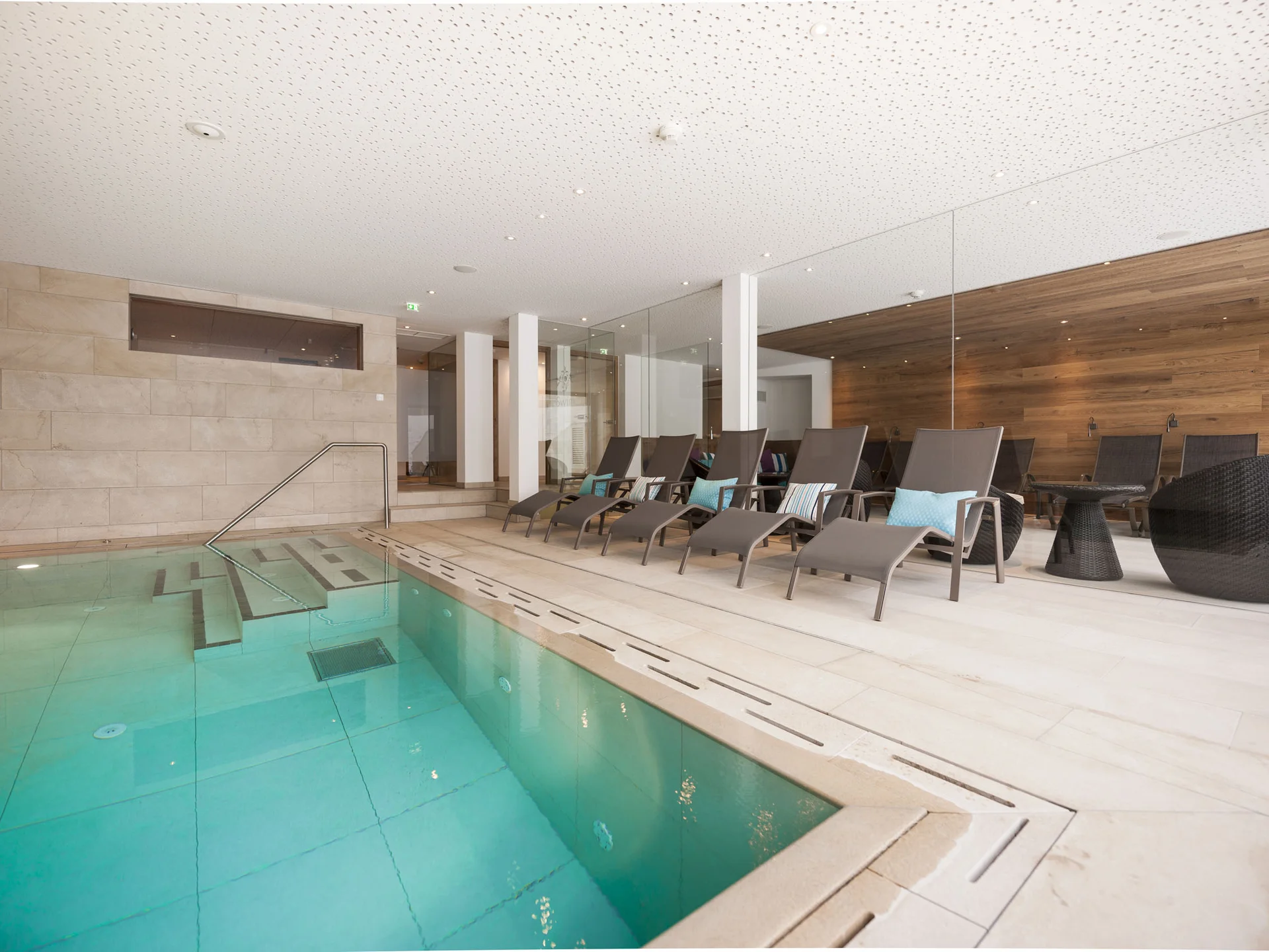 Moderner Innenpool mit Liegestühlen und Holzverkleidung an der Wand
