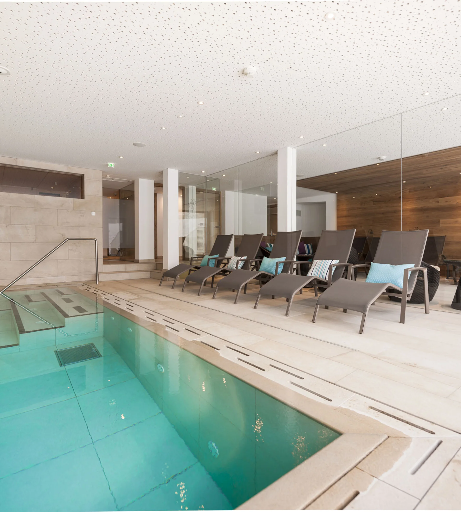 Moderner Innenpool mit Liegestühlen und Holzverkleidung an der Wand