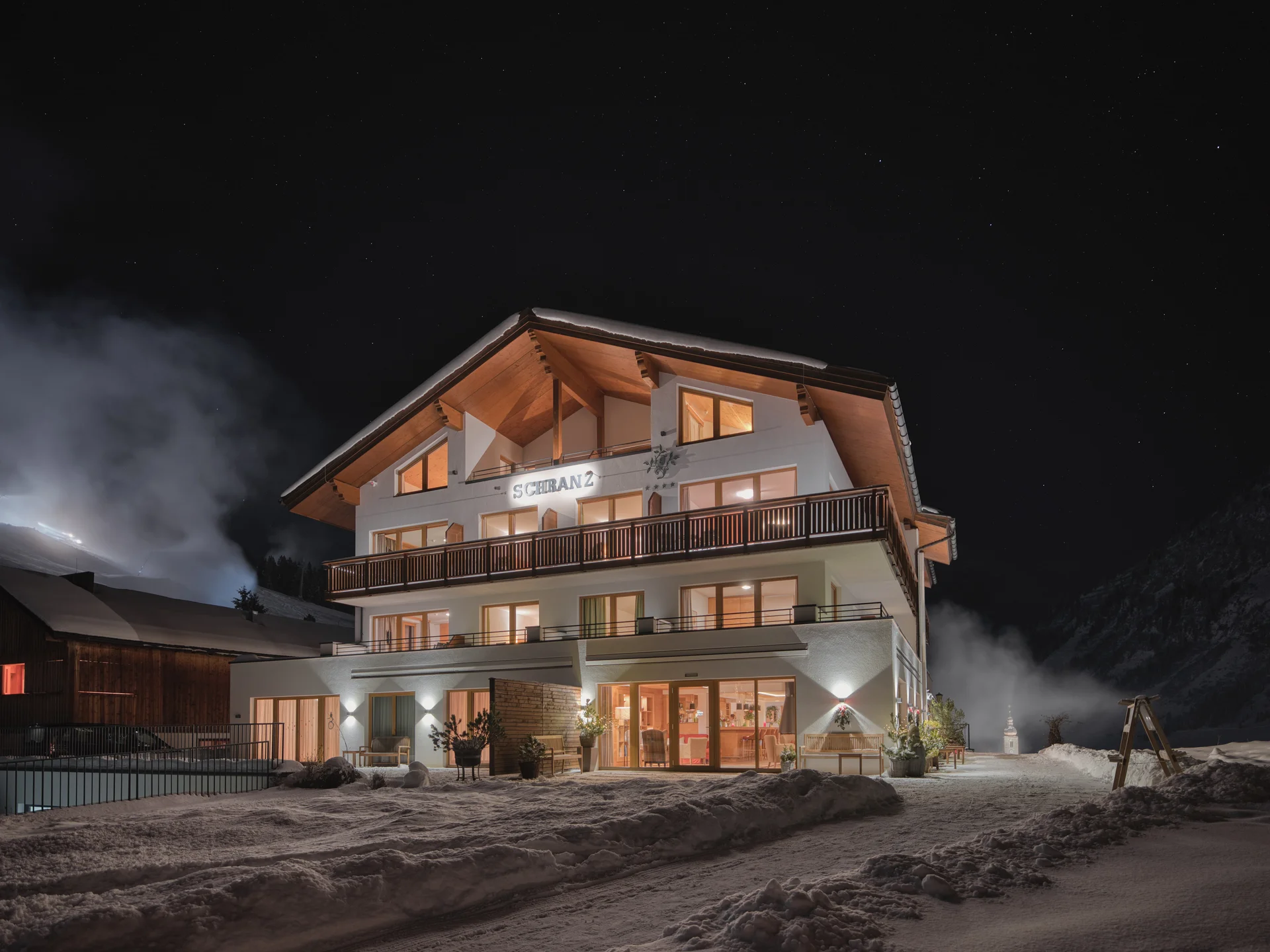 Bilder und Impressionen aus dem Sunora Beleuchtetes Chalet im Schnee bei klarem Nachthimmel mit Sternen