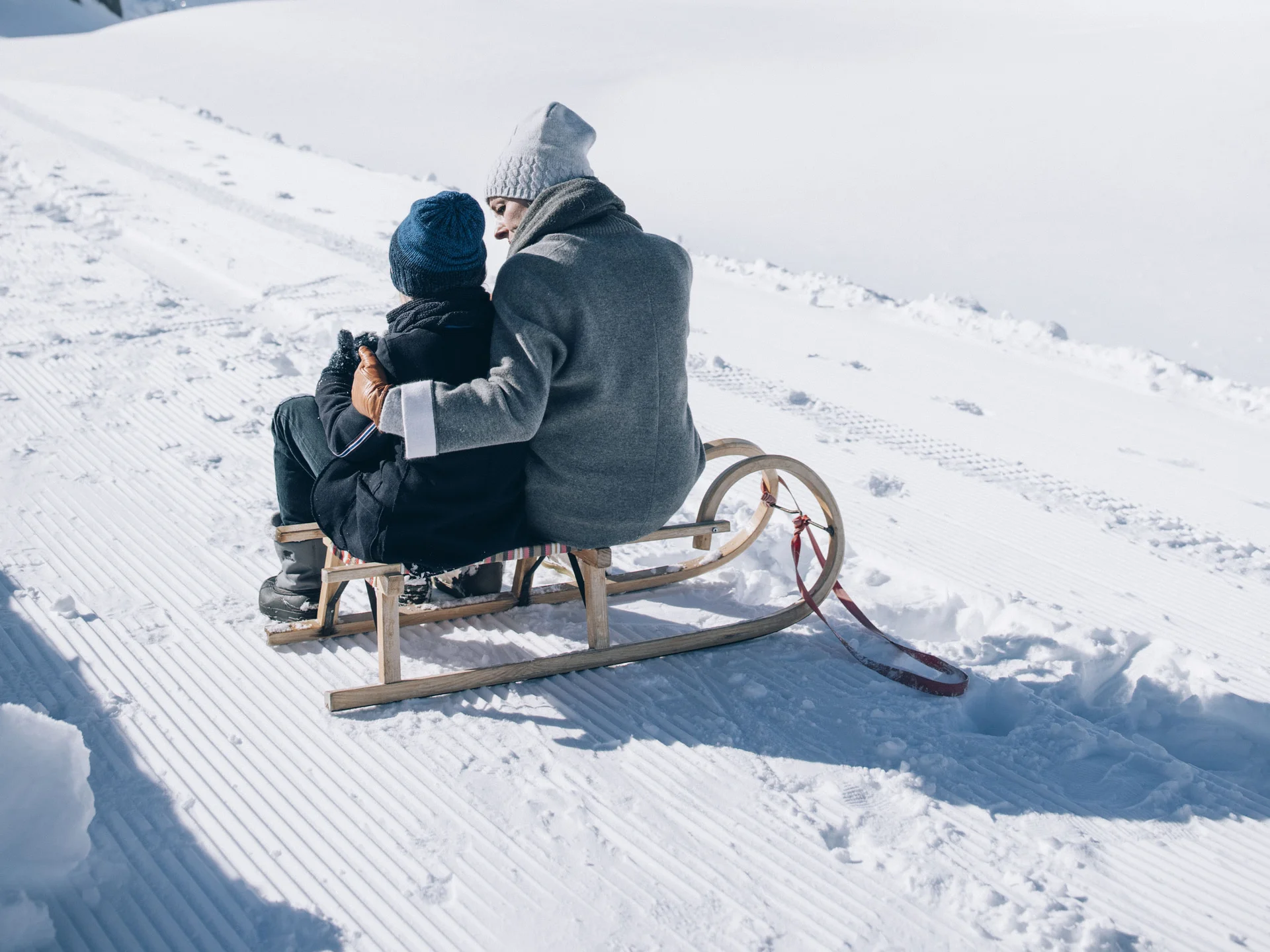 People on a sled in snowy mountain landscape under clear sky