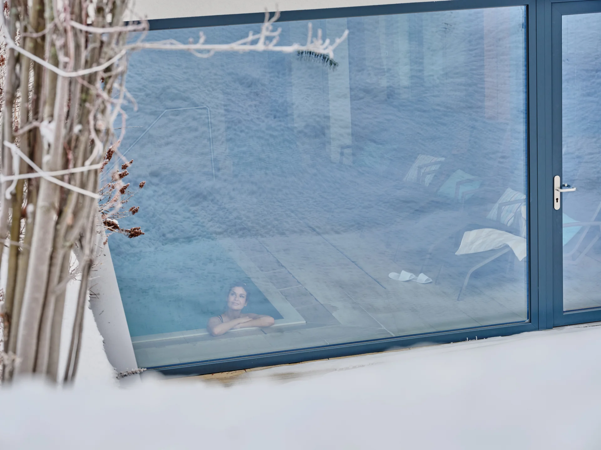 Bilder und Impressionen aus dem Sunora Frau entspannt sich im Innenpool eines Hauses mit großem Fenster