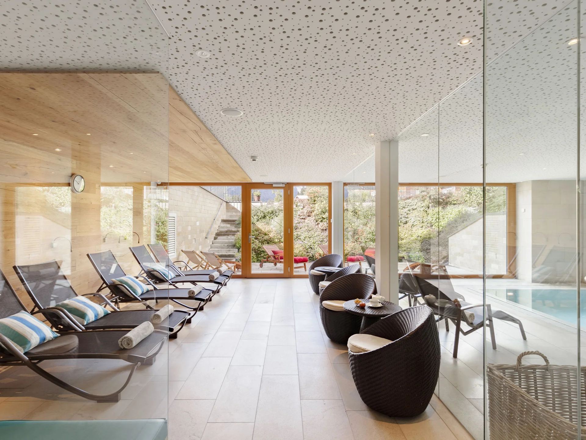 Innenraum mit Liegestühlen und Sitzecke neben einem Glasbecken