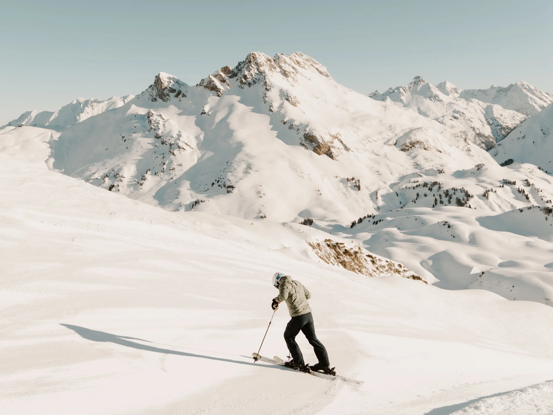 Skifahrer vor schneebedeckten Gipfeln in klarer Berglandschaft