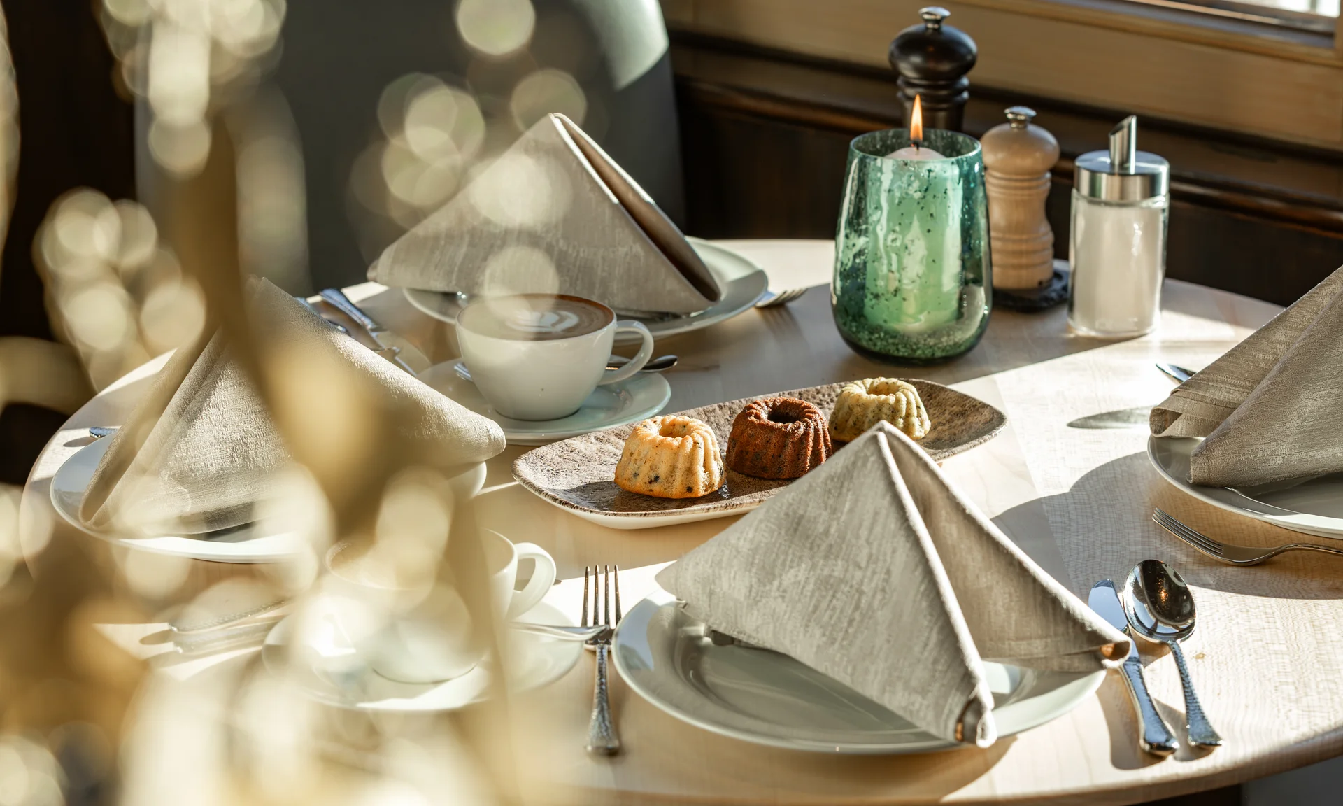 Eingedeckter Tisch mit Kaffee, Kuchen, Kerze und Gewürzen im Restaurant