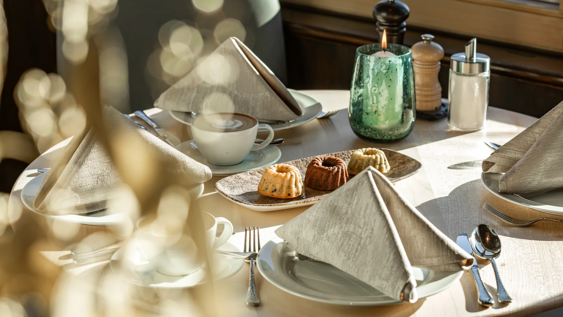 Eingedeckter Tisch mit Kaffee, Kuchen, Kerze und Gewürzen im Restaurant