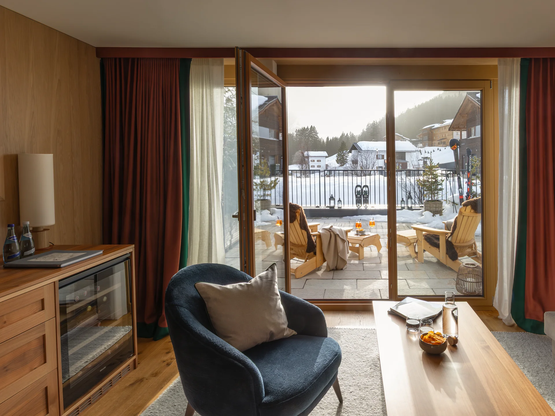 Gemütlicher Wohnbereich mit offenem Balkon und Blick auf verschneite Häuser und Berge