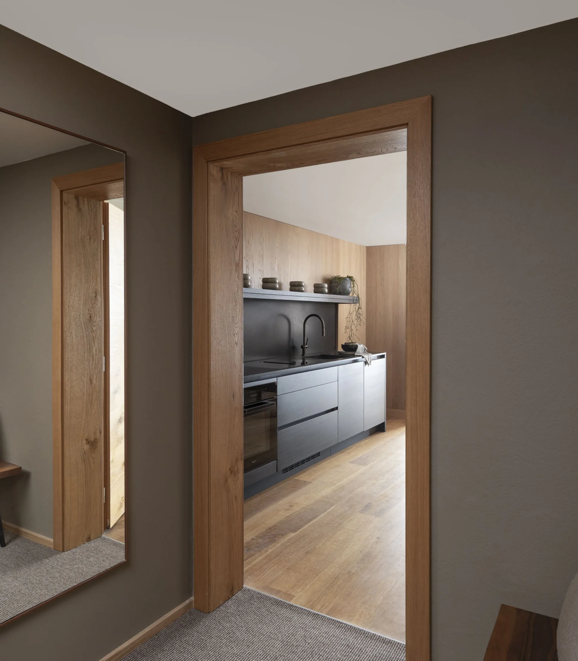 Flur mit großem Spiegel neben Holztür zum modernen Küchenbereich