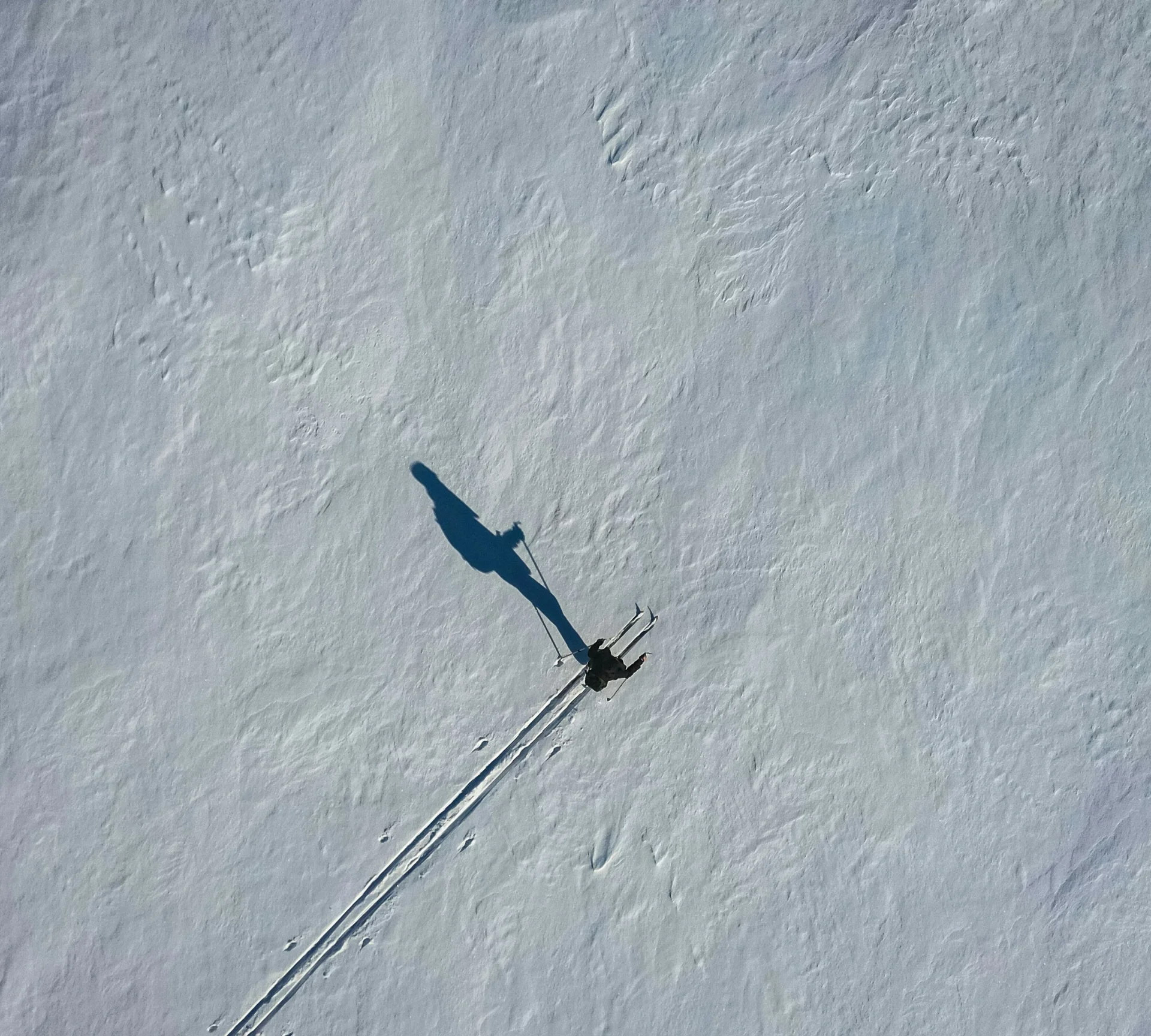 Ein Skifahrer fährt auf Schnee mit Schatten und Spuren im Schnee