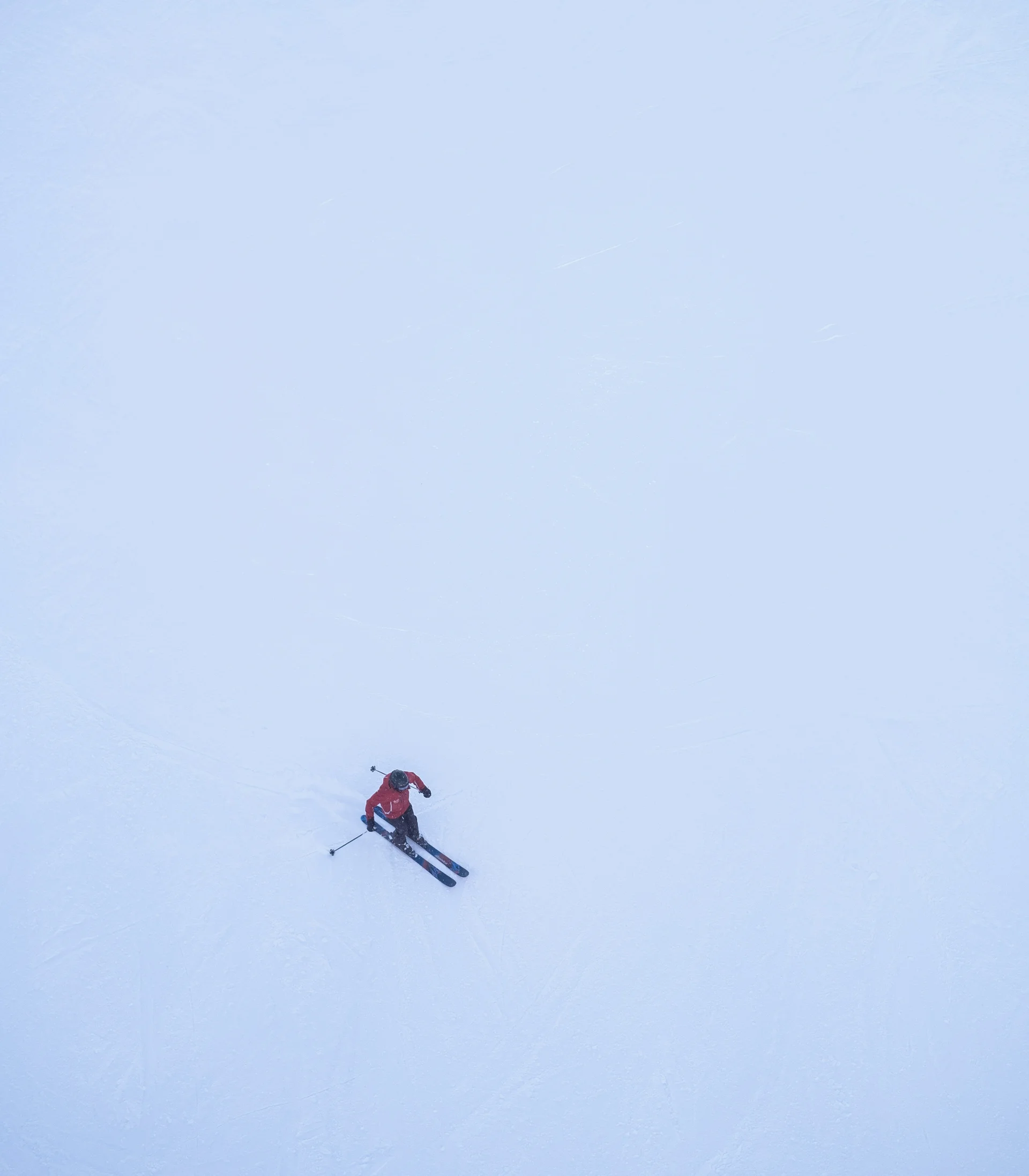 Skifahrer in roter Jacke auf verschneiter Piste aus der Vogelperspektive