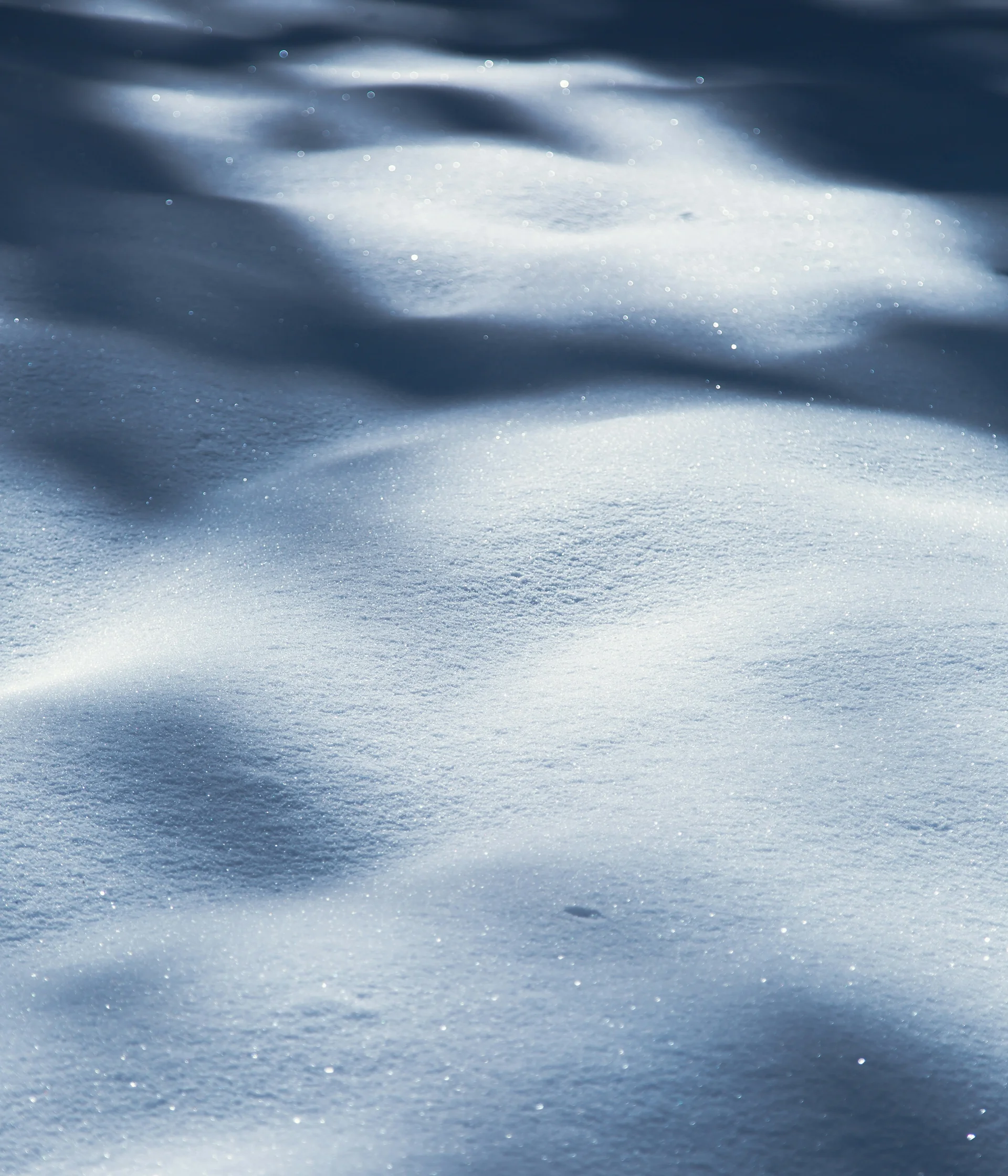 Nahaufnahme von schimmerndem Schnee mit Licht- und Schatteneffekten