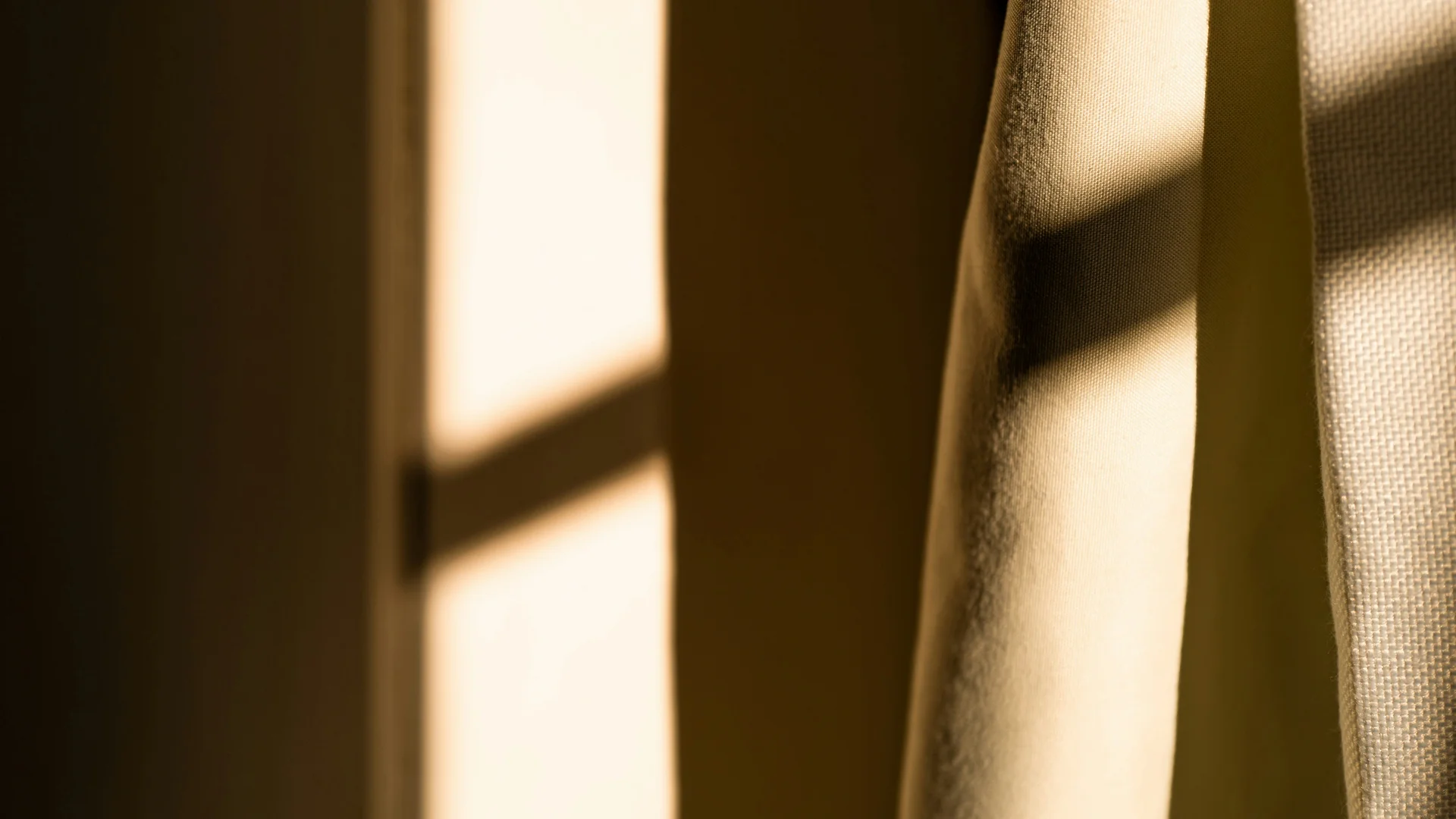 Sonnenlicht fällt durch ein Fenster und beleuchtet beige Vorhänge