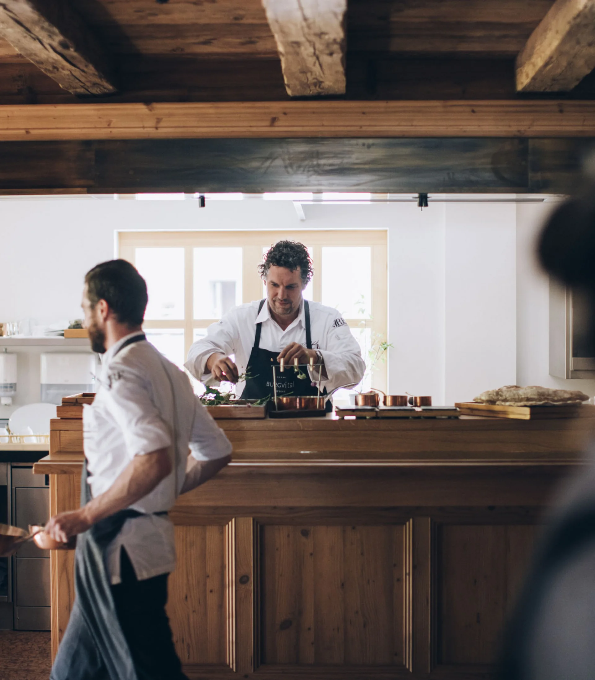 Köche arbeiten in einer rustikalen Küche mit Holzdecke und Küchenutensilien
