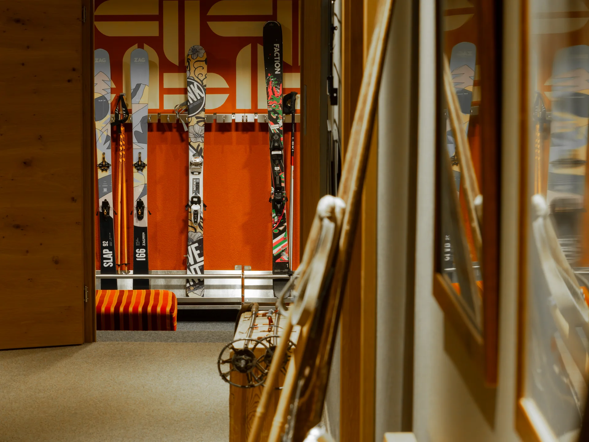 Skier und Skistöcke in einem Skiraum mit orangefarbenem Hintergrund