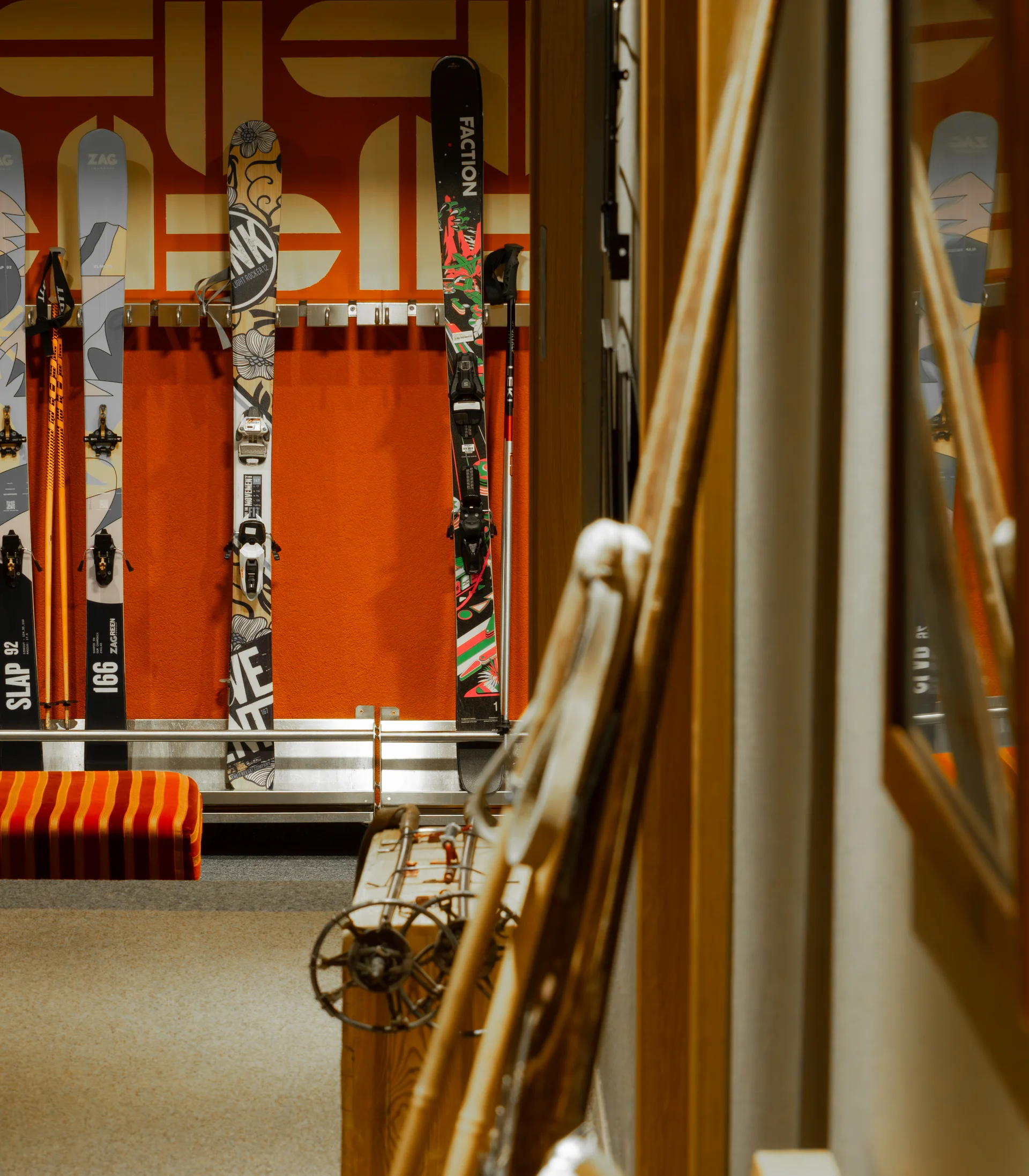 Skier und Skistöcke in einem Skiraum mit orangefarbenem Hintergrund