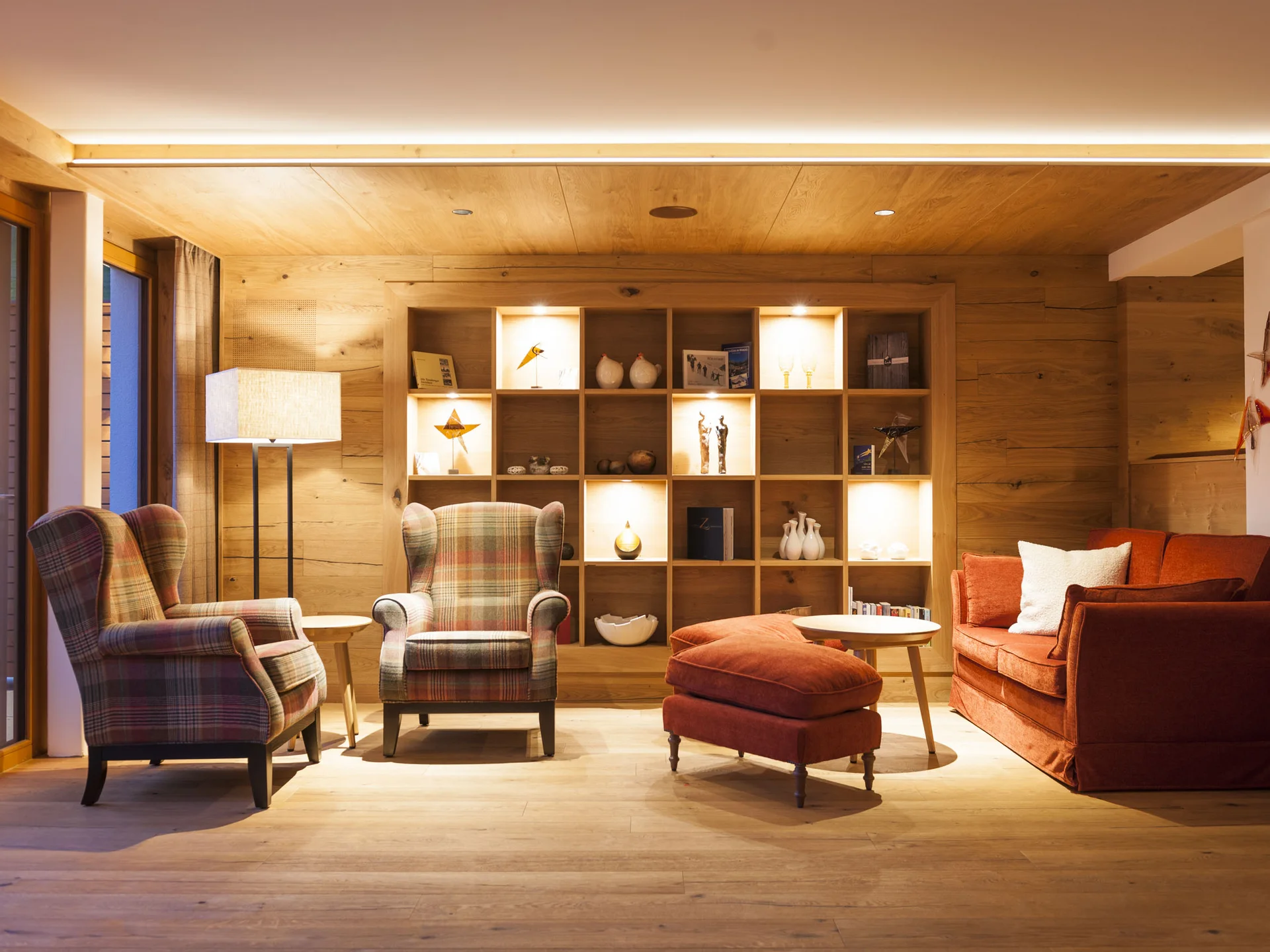 Gemütliches Wohnzimmer mit Holzwänden, Sessel und Regal mit Dekoration