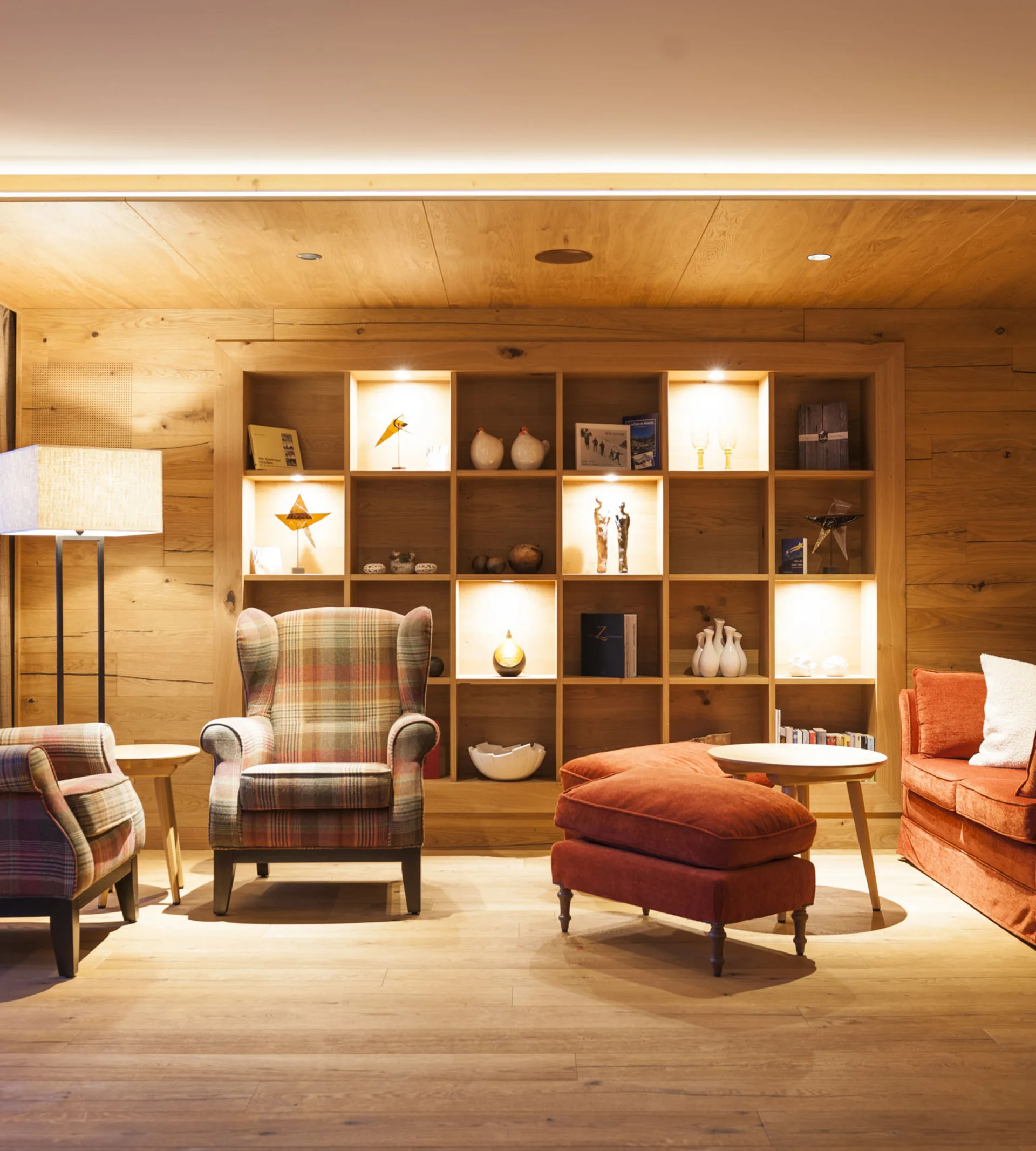 Gemütliches Wohnzimmer mit Holzwänden, Sessel und Regal mit Dekoration