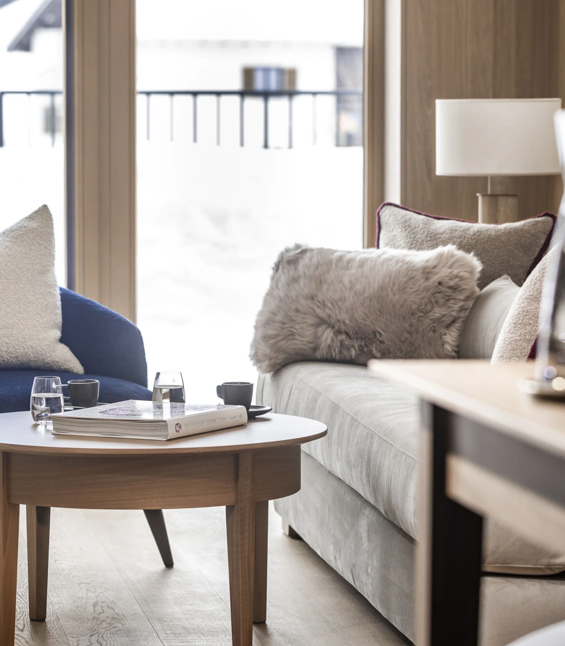 Gemütlicher Wohnbereich mit Sofa, Sesseln und einem Holztisch vor Fenster