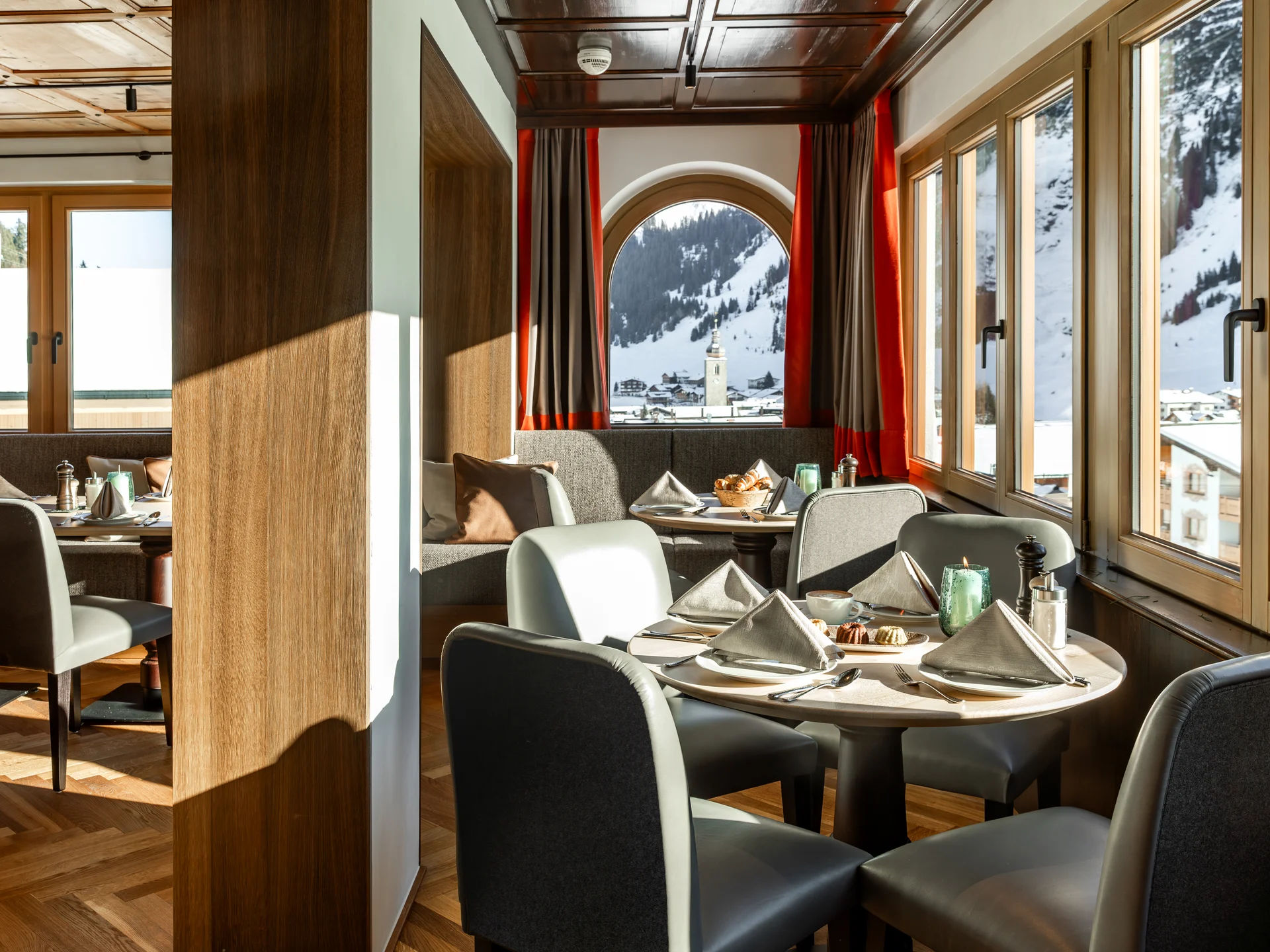 Gemütlicher Essbereich mit Bergblick durch große Fenster in einem Holzdekor-Restaurant