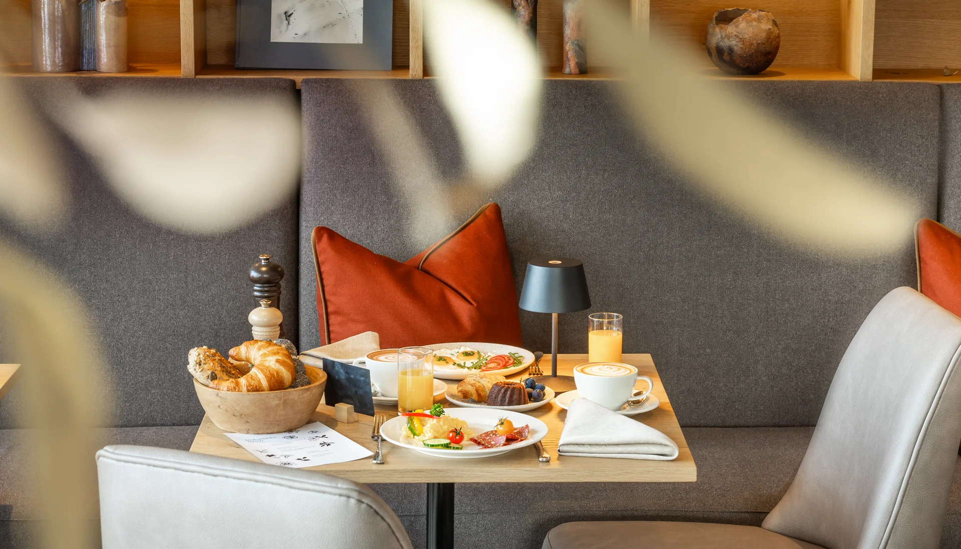 Gemütlicher Frühstückstisch mit Croissants, Eiern und Getränken in modernem Café