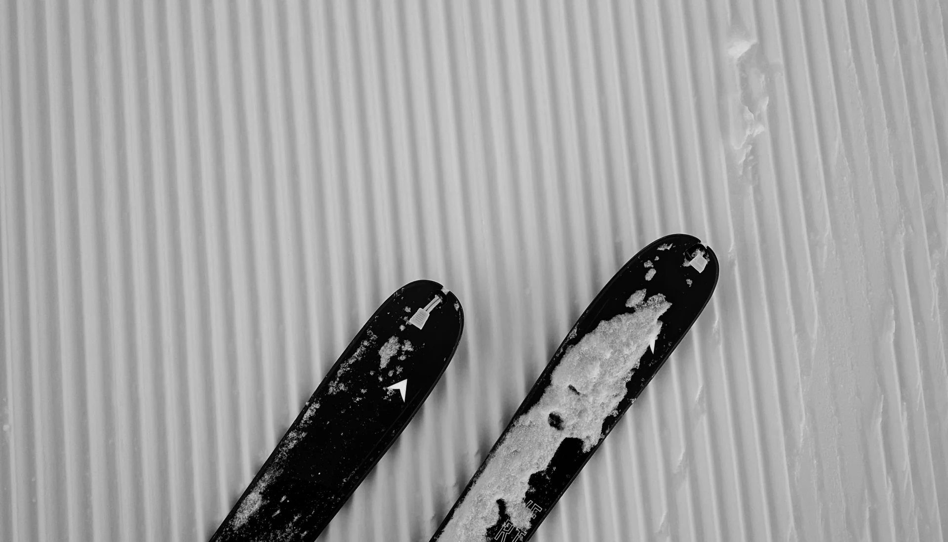 Skier auf frisch präparierter Piste mit Schnee und parallelen Spuren