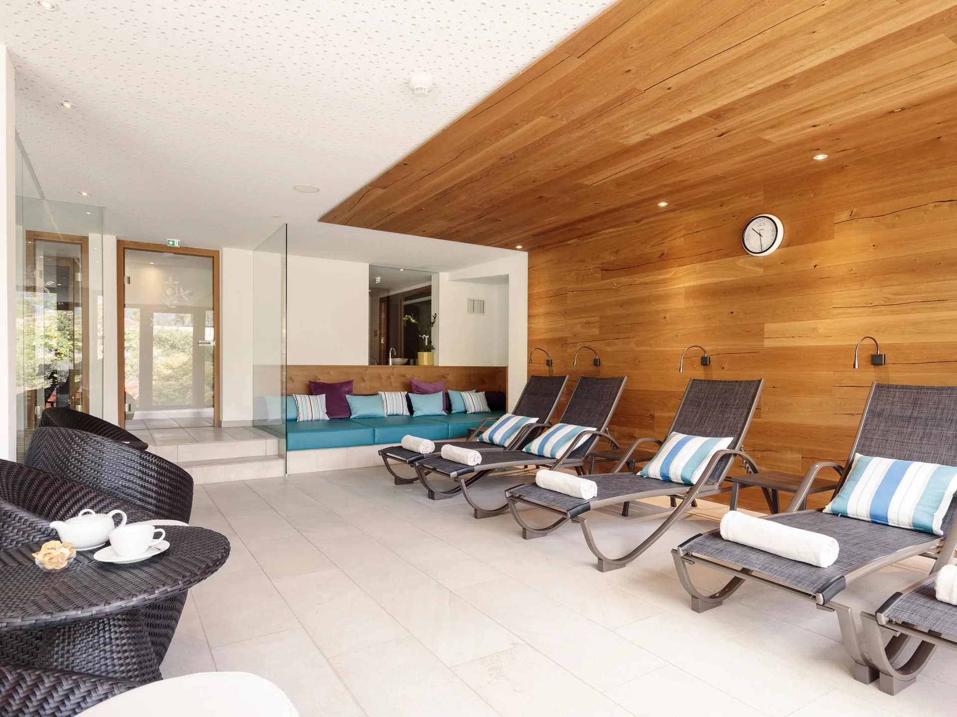 Moderne Lounge mit Holzvertäfelung, Liegestühlen und Teetisch