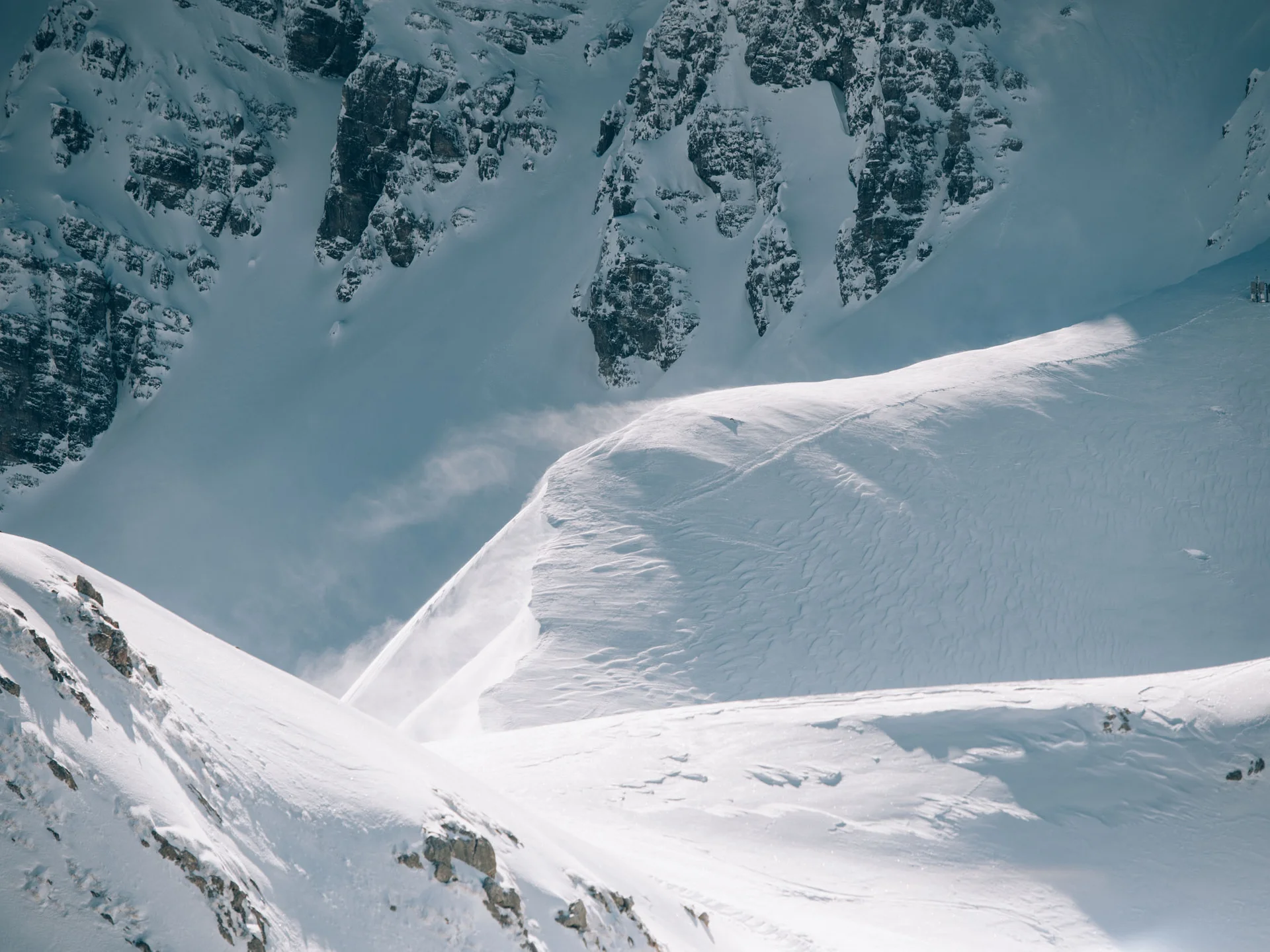 Schneebedeckte steile Berghänge mit felsigen Abschnitten im Winter