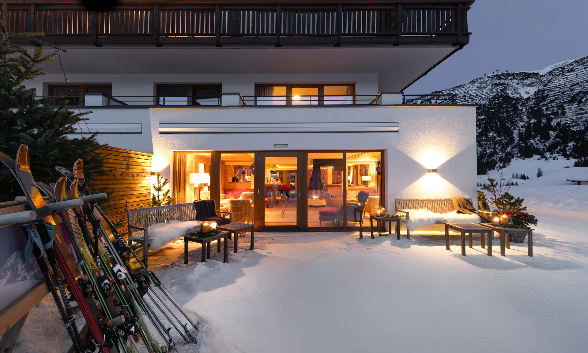 Skier vor beleuchtetem Chalet Schiarnz im verschneiten Bergdorf bei Dämmerung