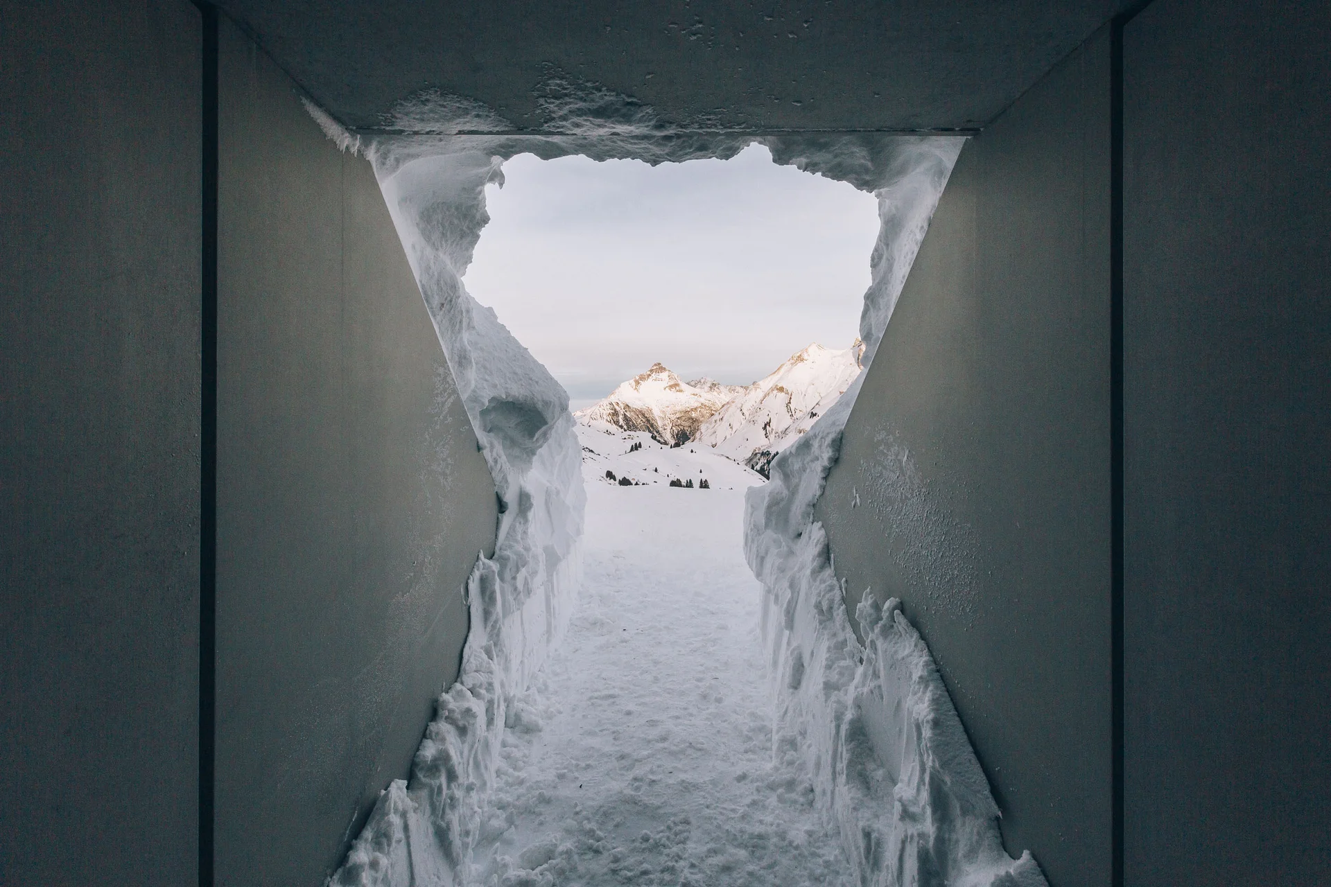 Blick durch ein schneebedecktes Fenster auf verschneite Berge
